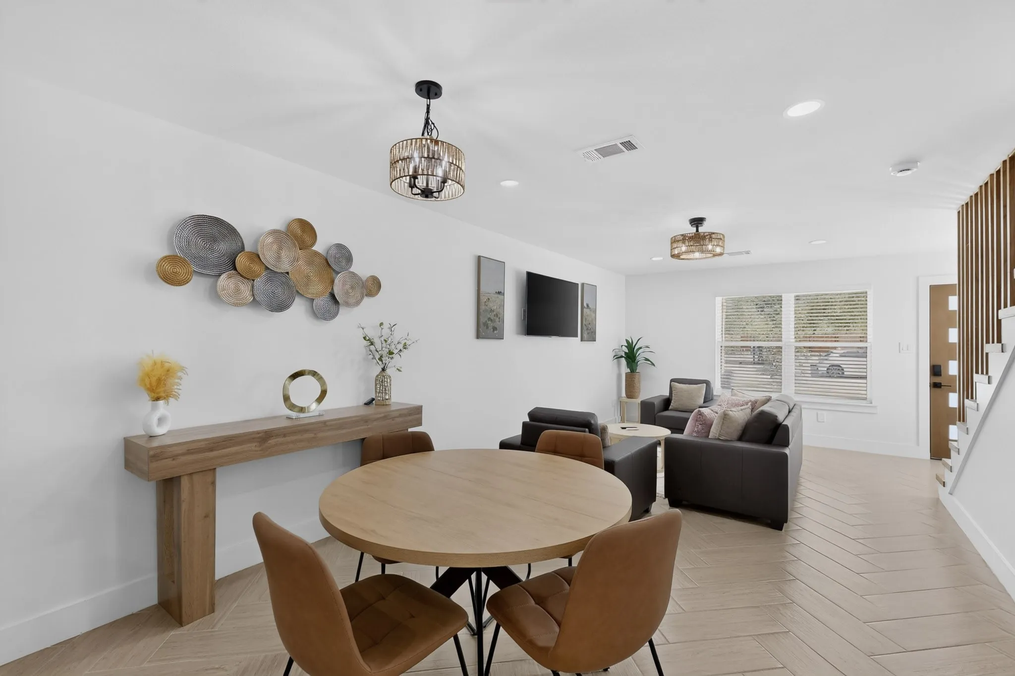 Open-concept living area with light wood-finish flooring, recessed lighting, and a modern chandelier