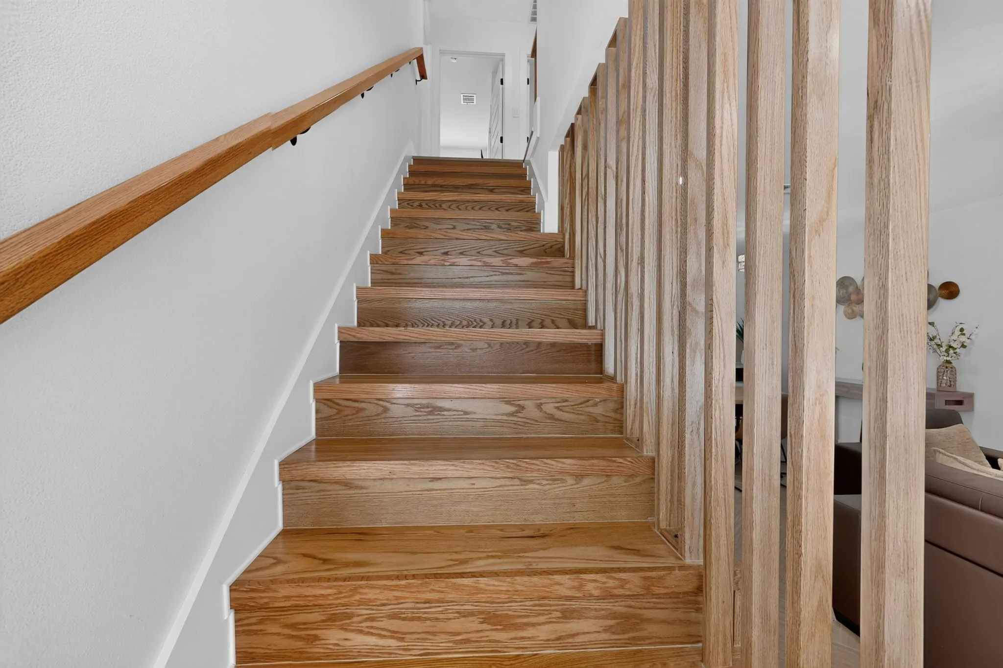 Staircase featuring wood steps, wood handrail, and vertical wood slat railing