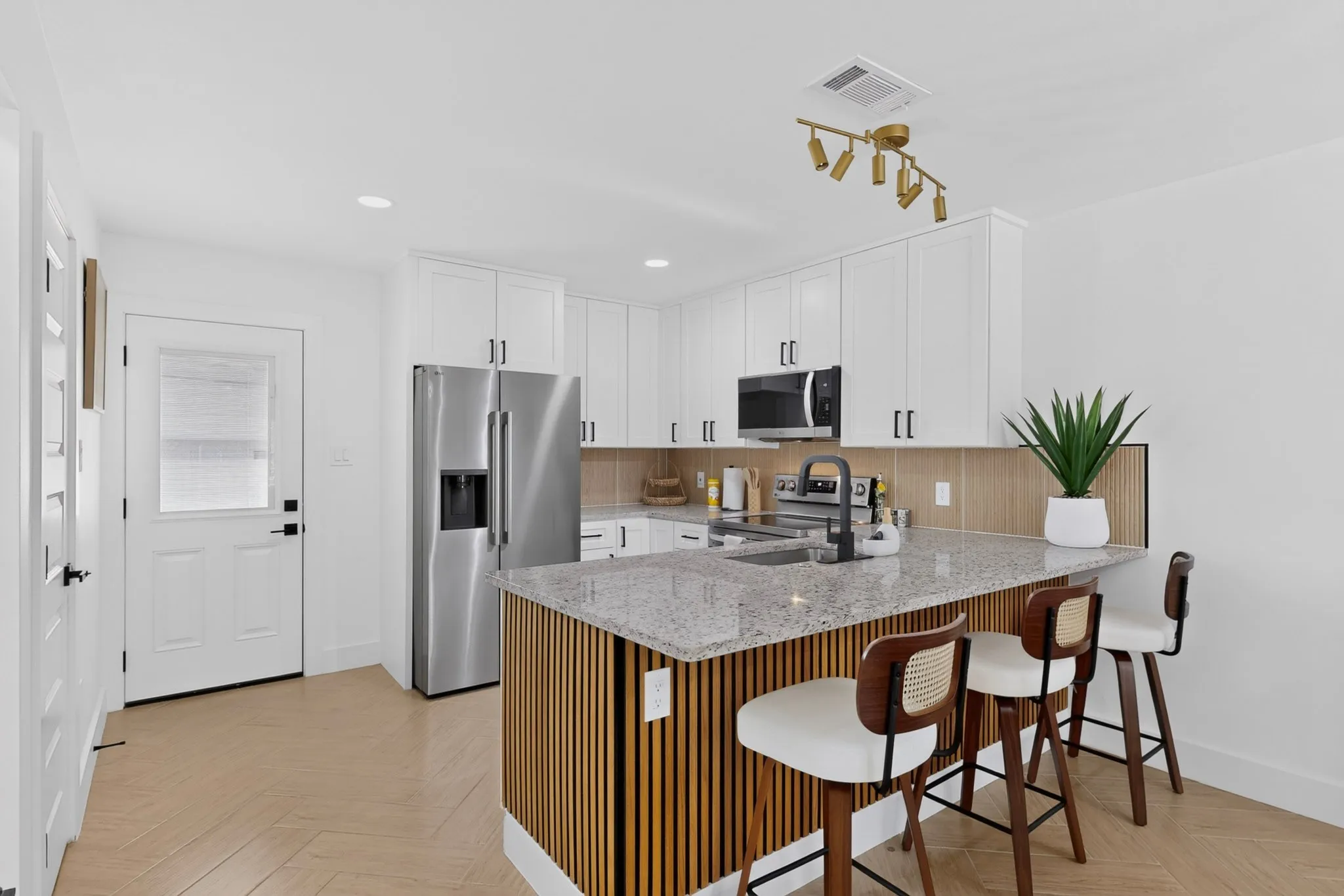 White shaker cabinetry, stainless steel appliances, granite countertops, and wood-finish flooring