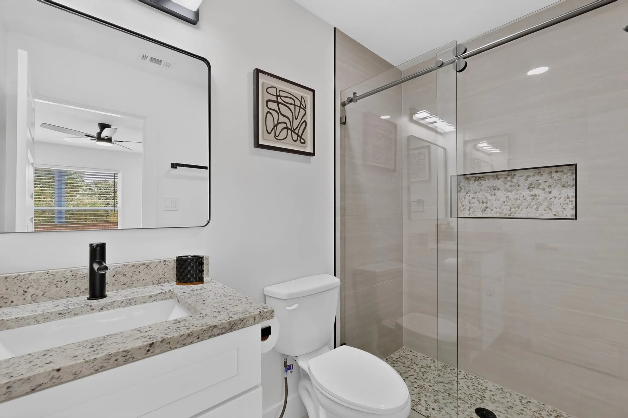 Bathroom featuring a vanity with a light-toned speckled countertop, undermount sink, and matte black faucet