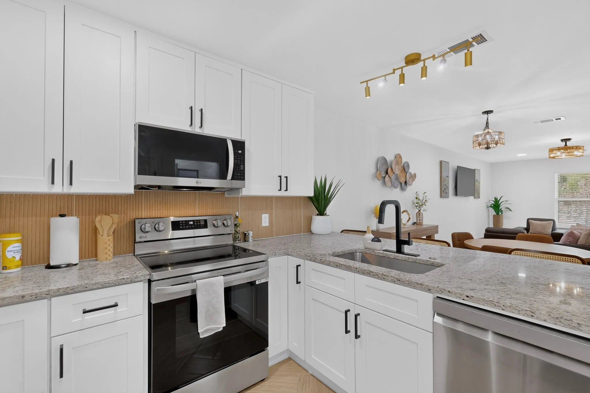 Kitchen featuring white shaker-style cabinetry, granite-finish countertops, stainless steel appliances, and a modern track lighting fixture