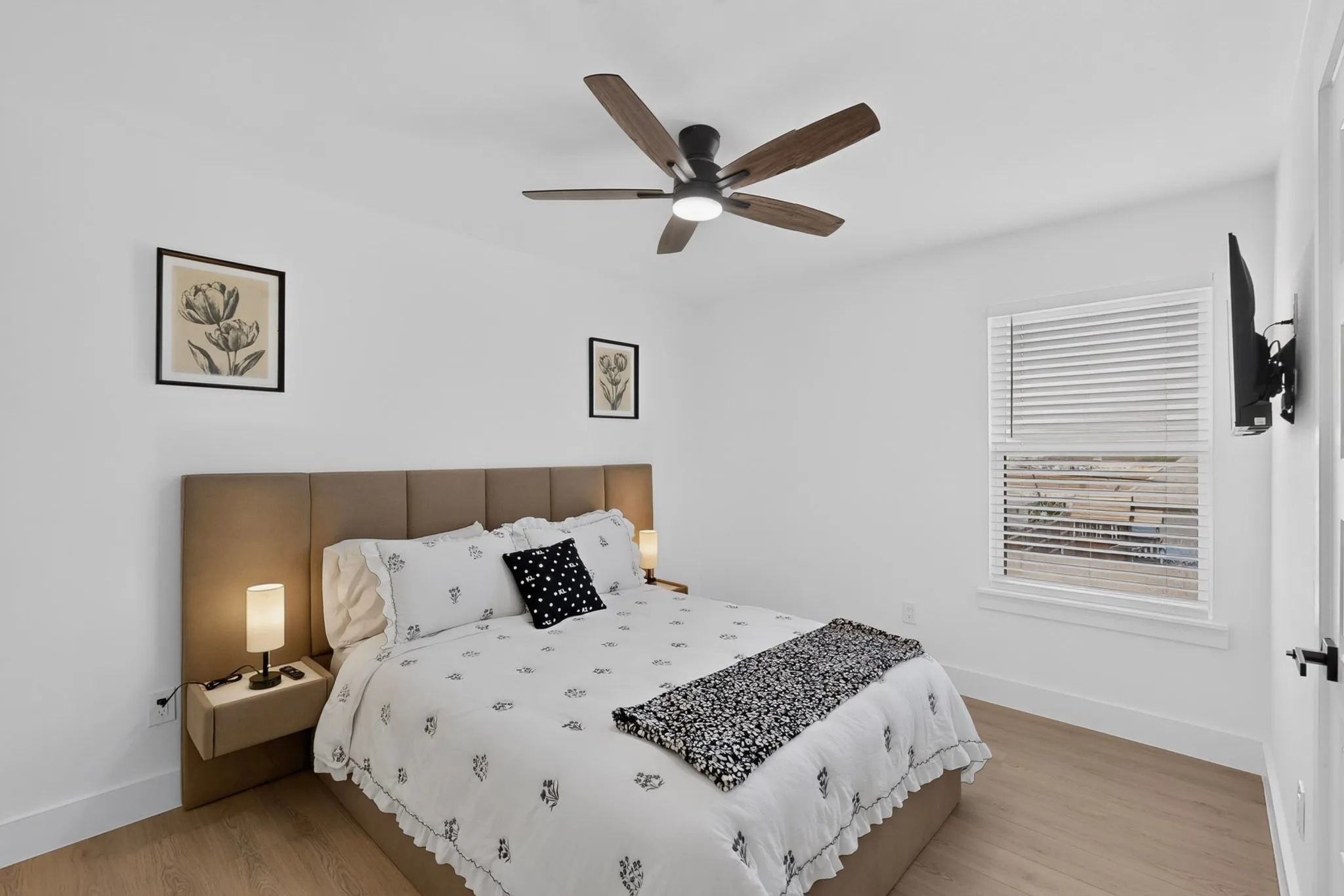 Wood-finish flooring, a window with blinds, a ceiling fan with integrated lighting, and white walls