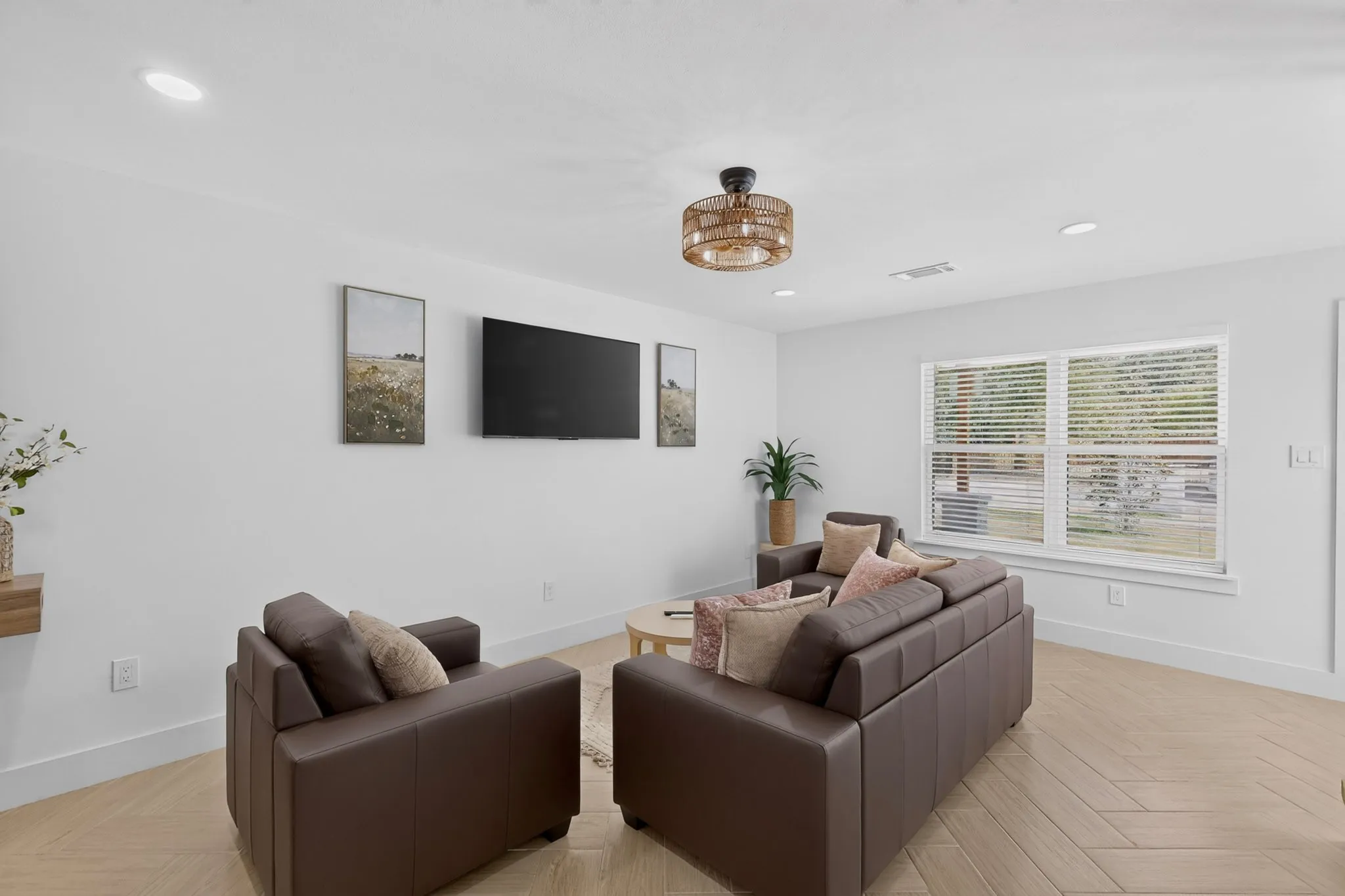 Recessed lighting illuminates the white walls and light-toned wood-finish flooring