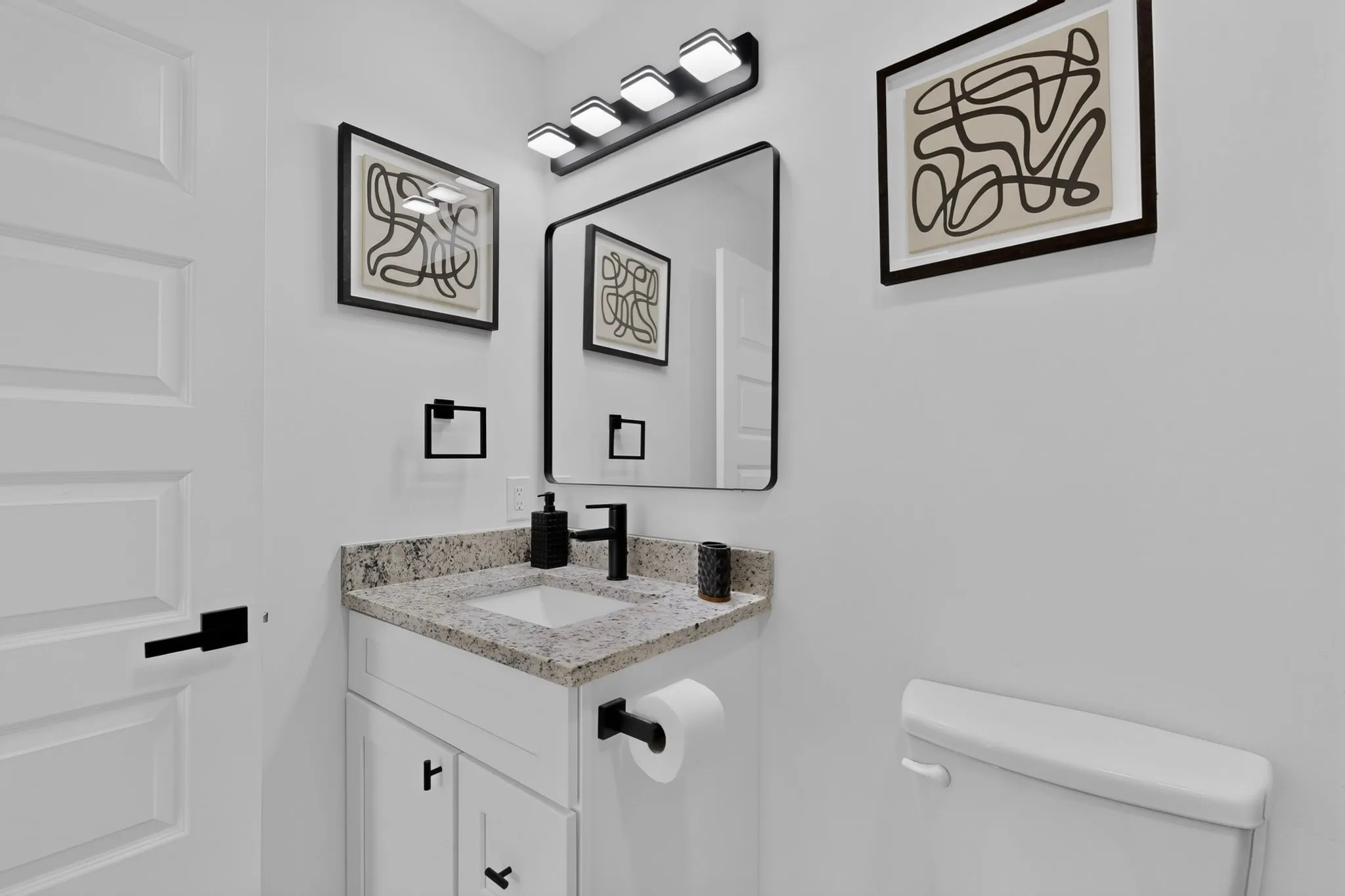 White shaker vanity with a granite countertop and integrated sink