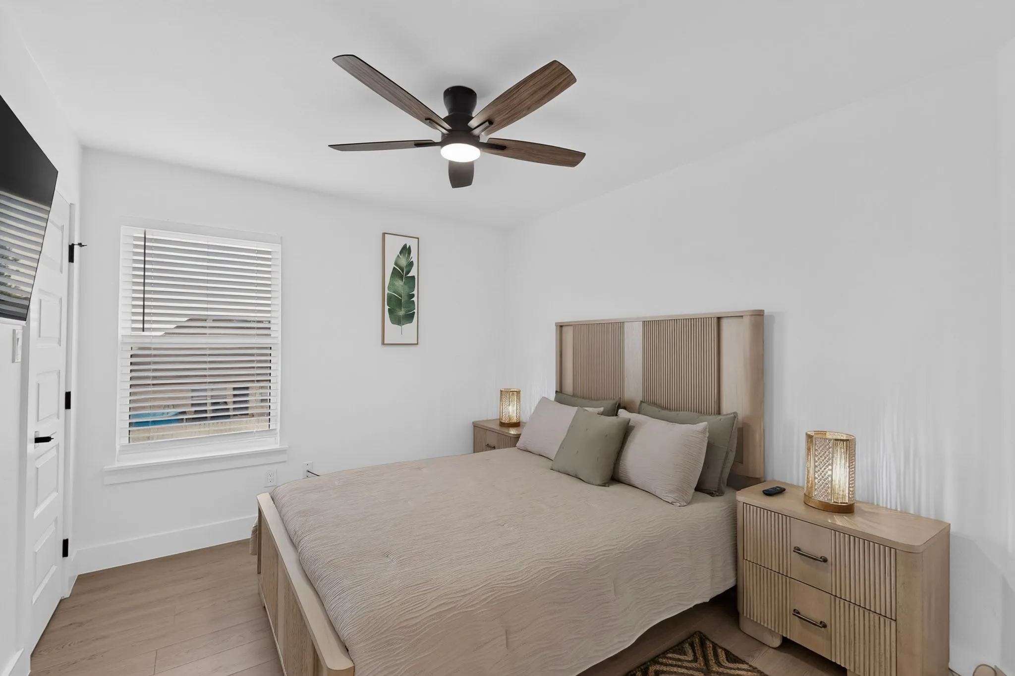 Light wood-finish flooring, a ceiling fan with integrated lighting, and a window with blinds