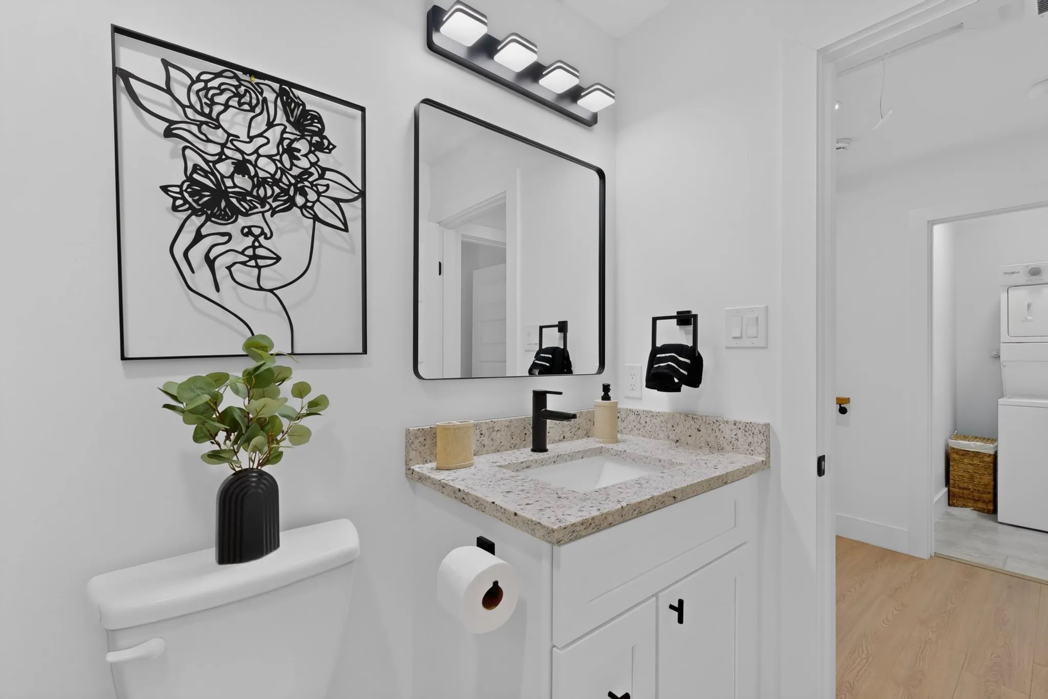 White vanity with black hardware, integrated sink, and speckled countertop
