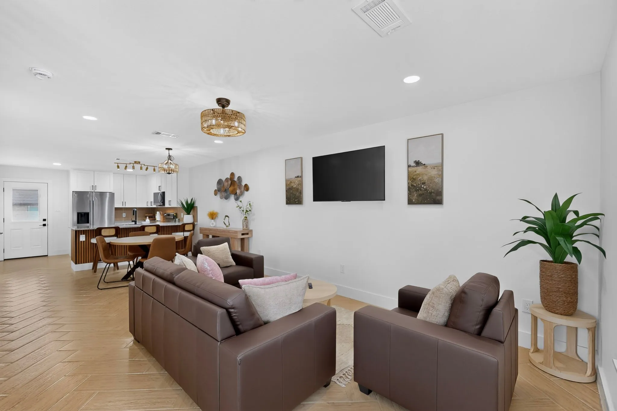 Open-concept living area featuring light-toned wood-finish flooring, white walls, and recessed lighting