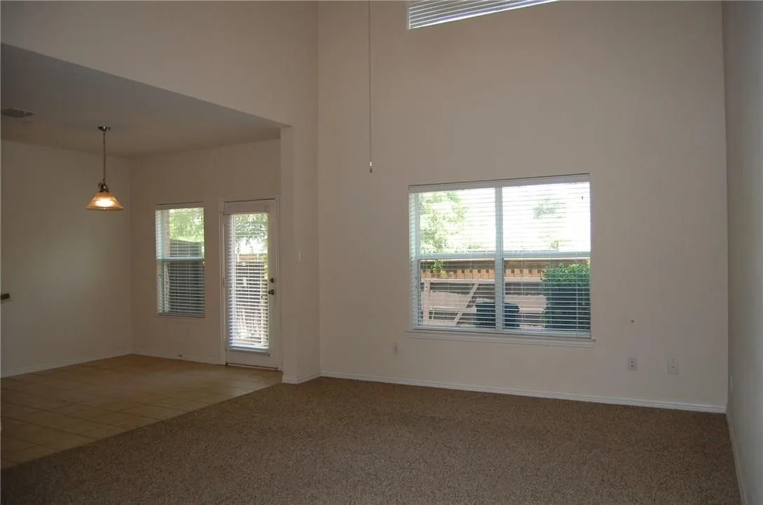 Living room featuring plenty of natural light, dark carpet, and a high ceiling