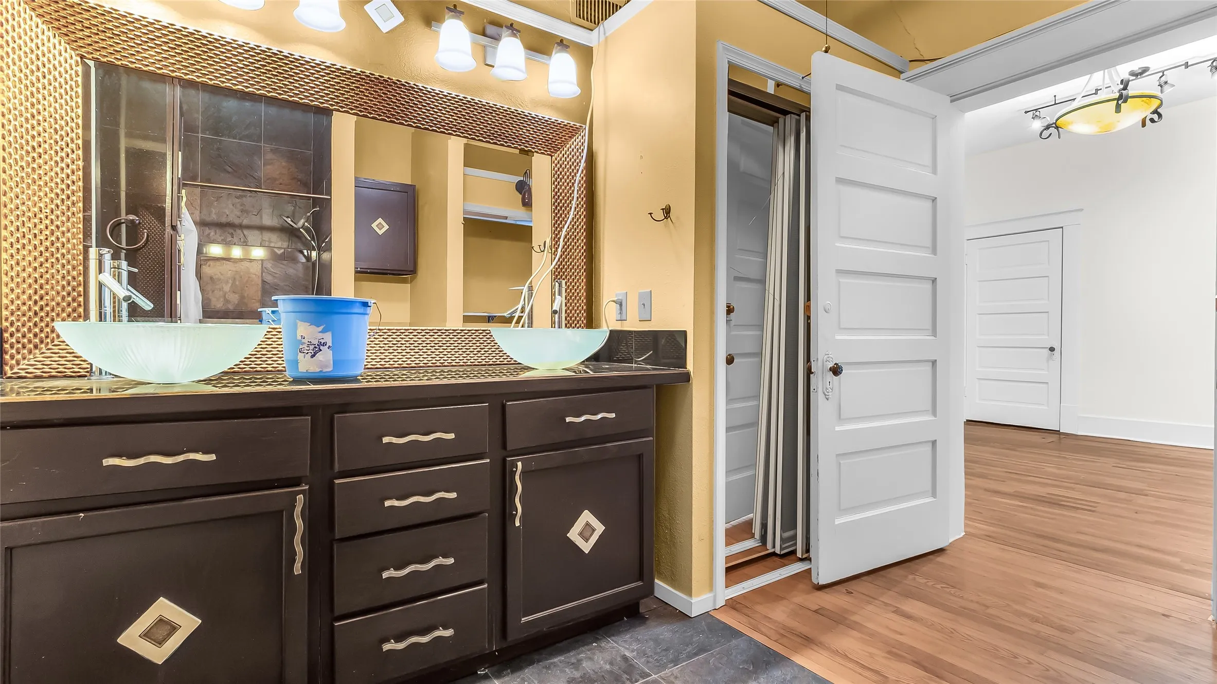 Double vanity with vessel sinks and track lighting, dark wood-finish cabinetry, and a large framed mirror