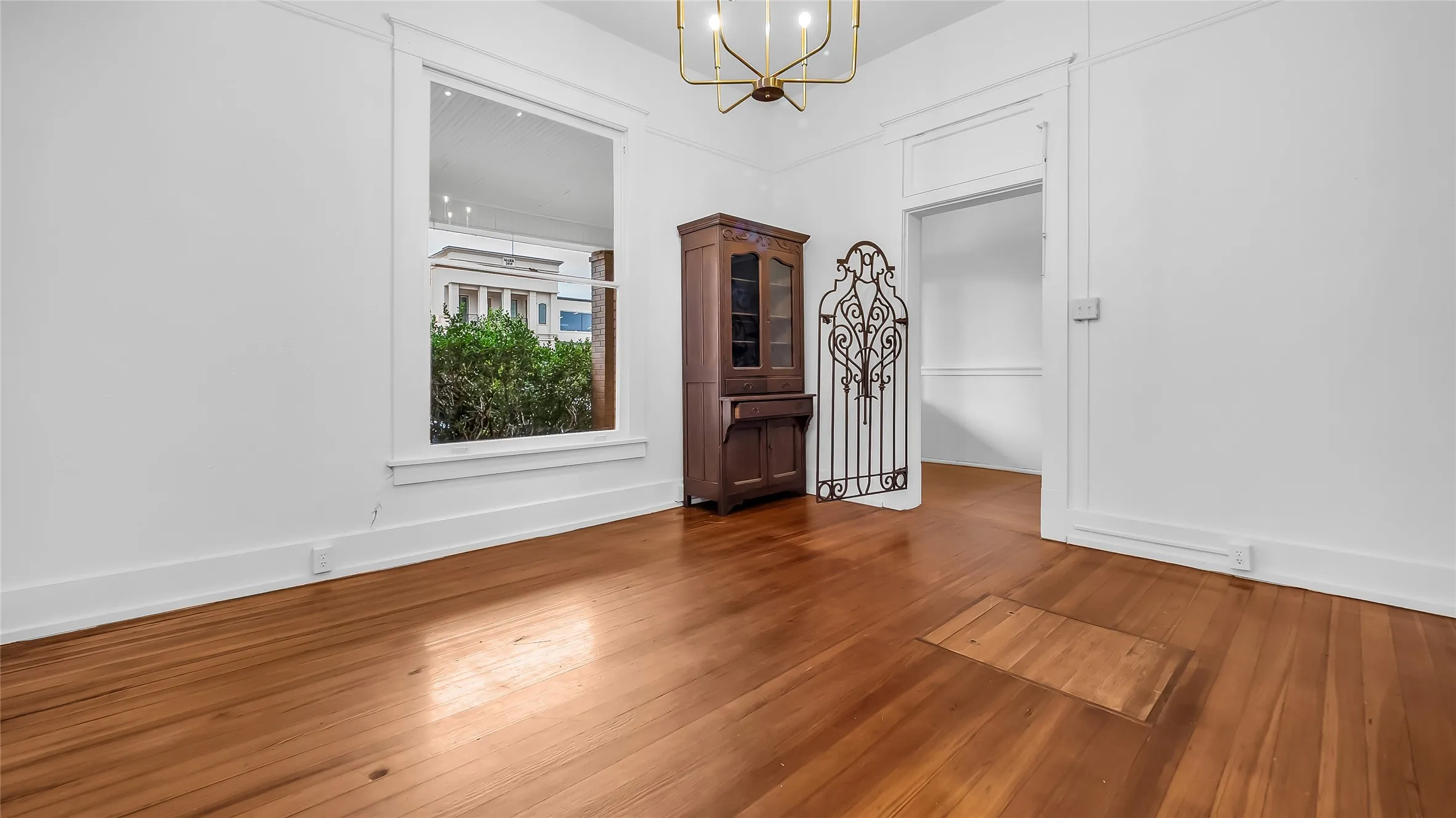 Hardwood flooring, painted white walls, recessed window, and overhead light fixture