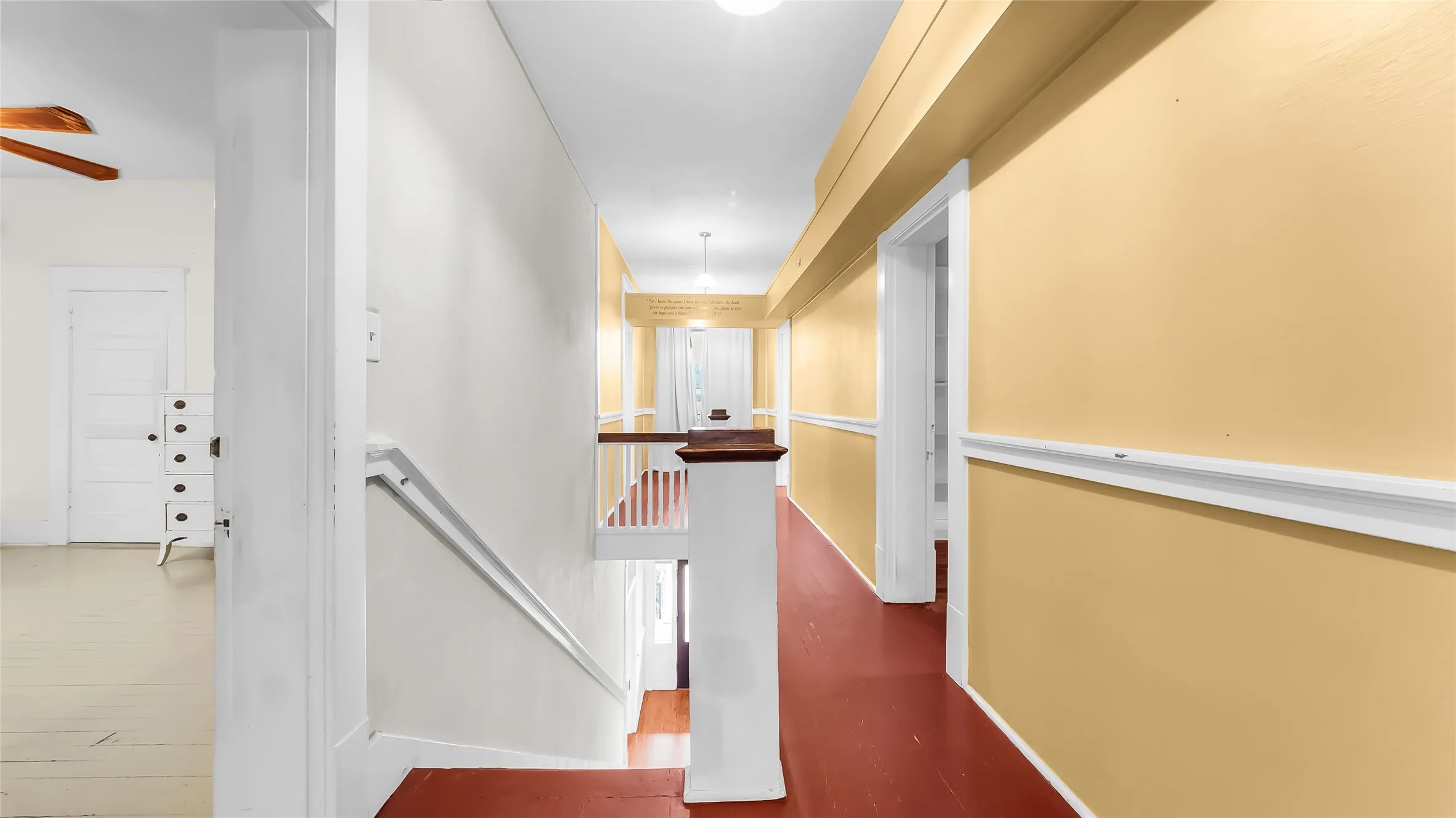 Upper-level hallway featuring a painted wood floor and white trim