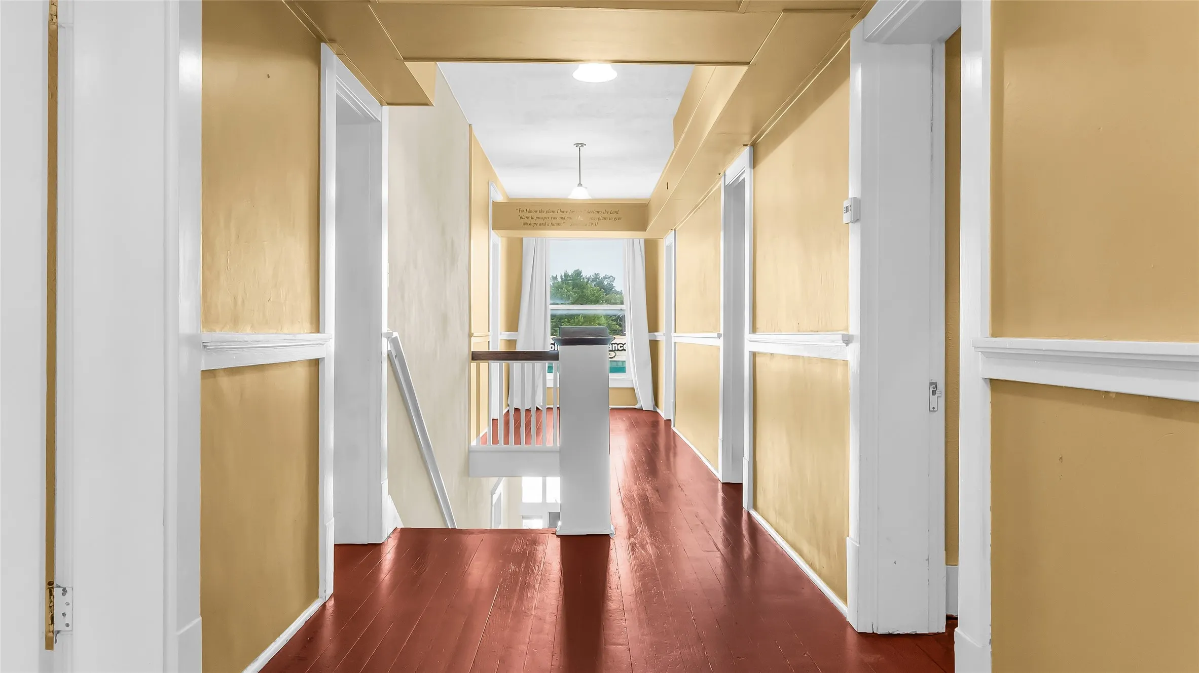 Hardwood flooring, painted paneled walls, white trim, and a built-in staircase