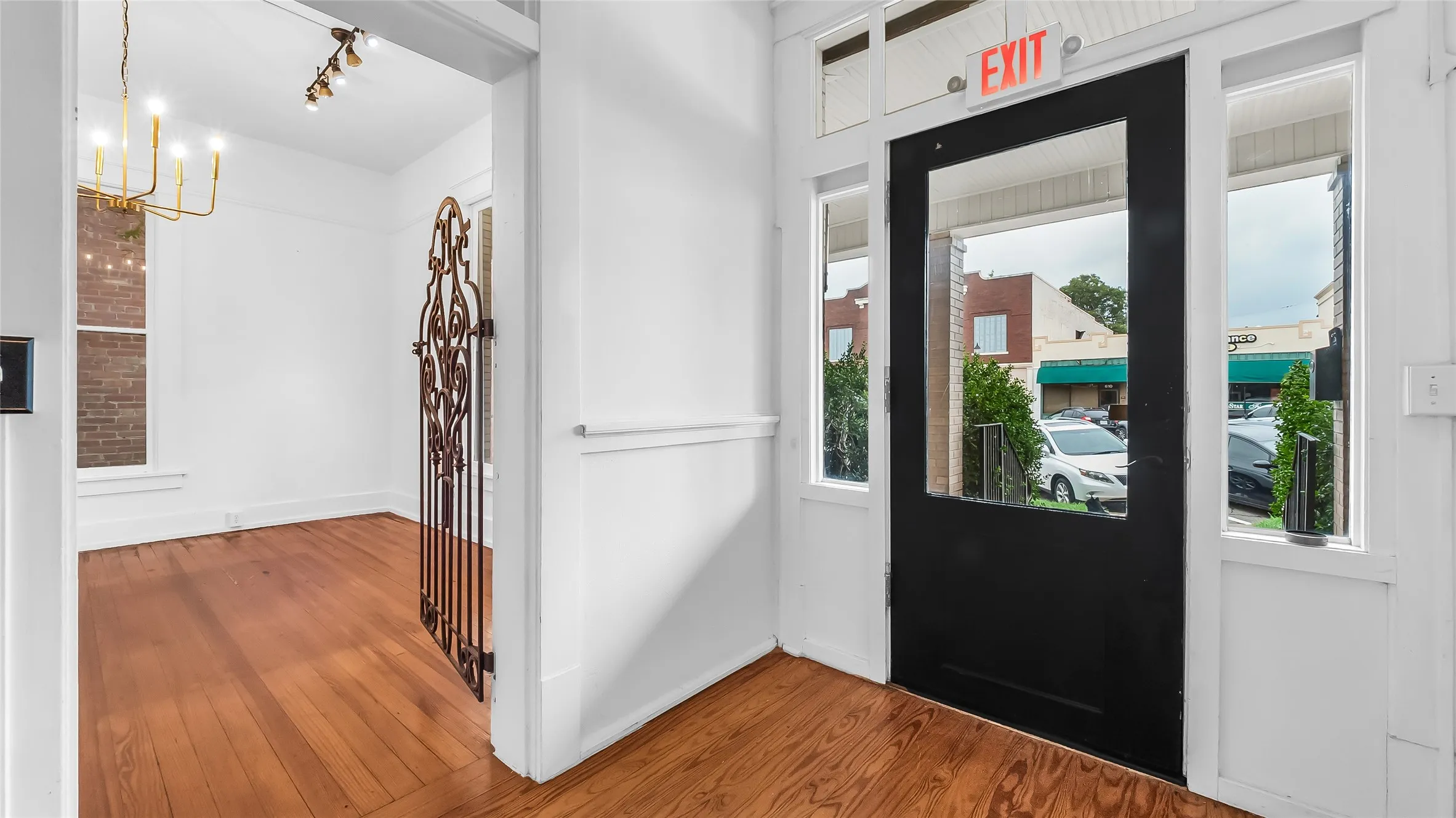 Hardwood flooring, white wall finishes, and a decorative wrought iron gate