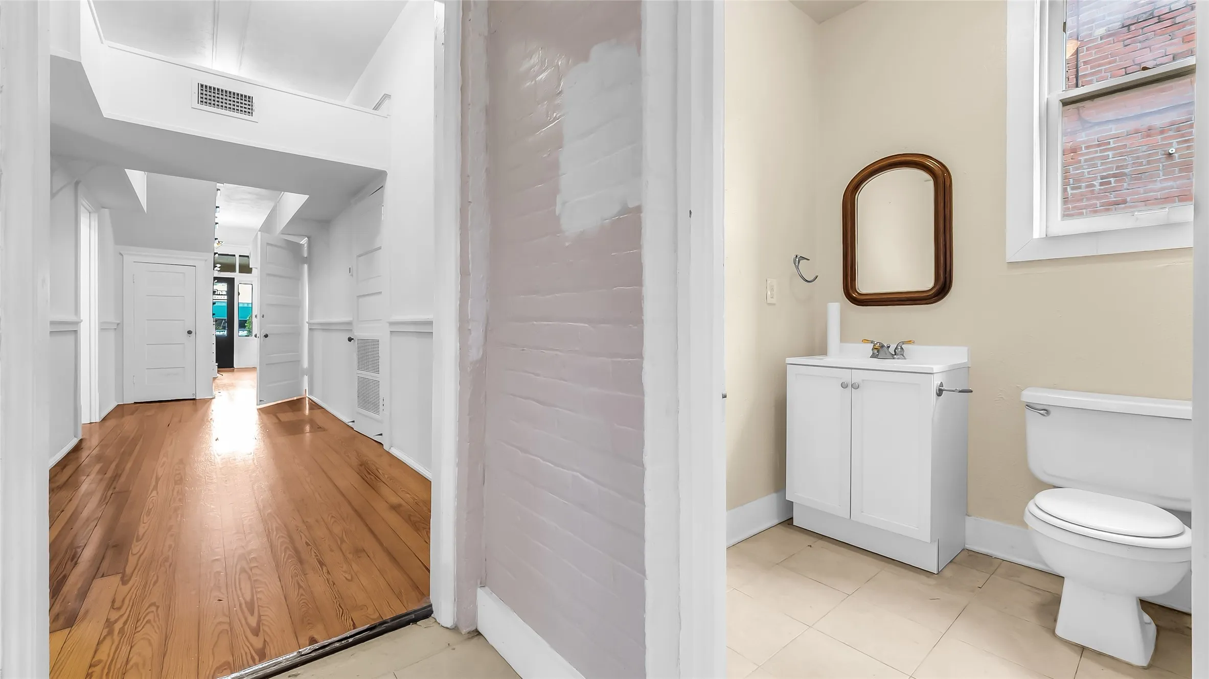 Hallway with wood-finish flooring and white paneled walls