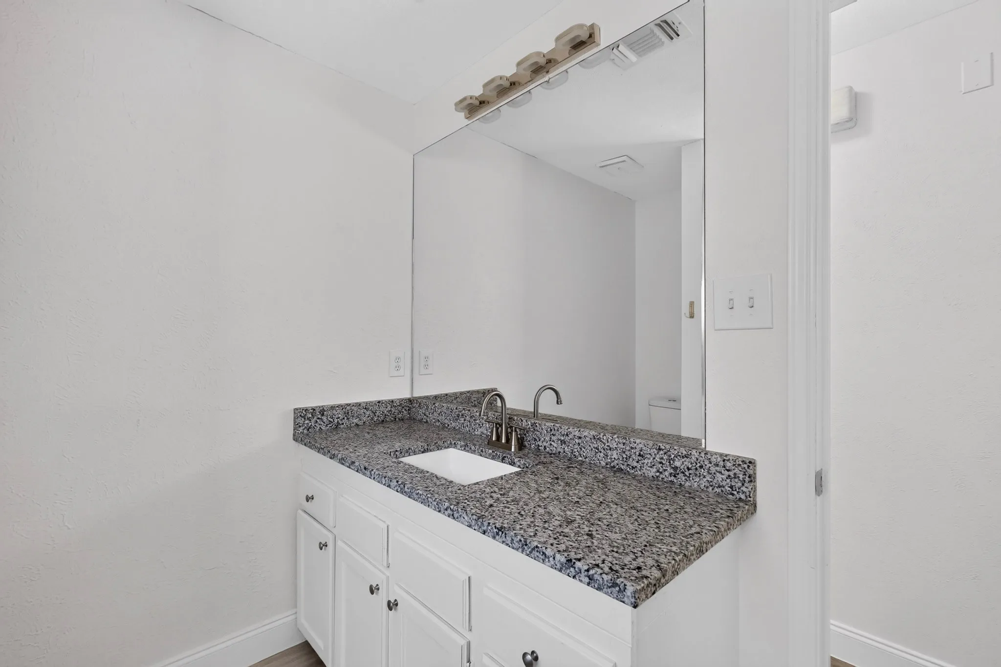 Vanity with a speckled countertop, undermount sink, and brushed nickel faucet