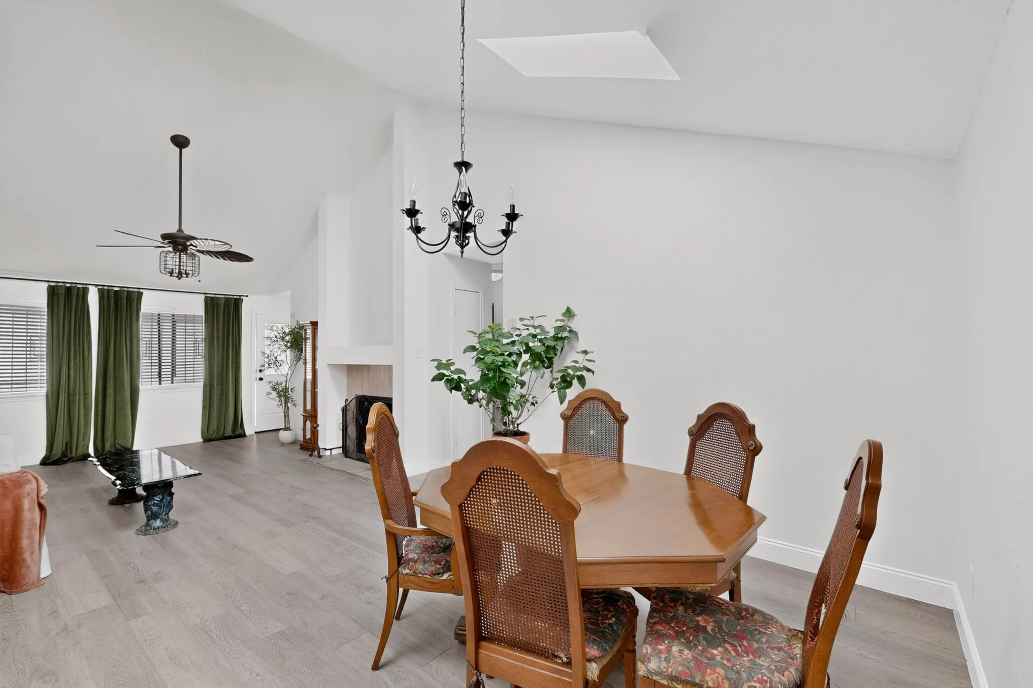 Vaulted ceiling, wood-finish flooring, fireplace, and two distinct overhead light fixtures