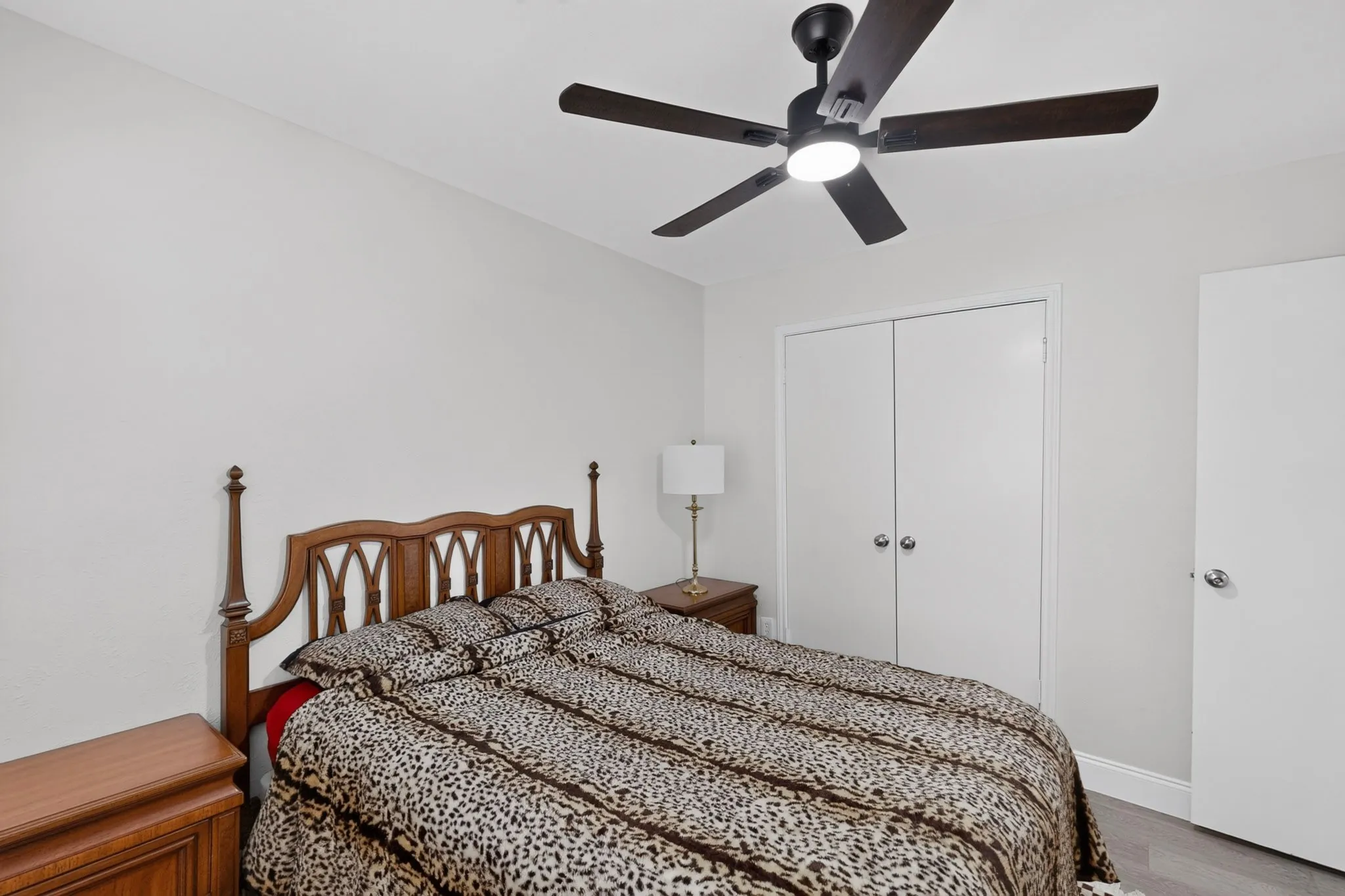 Ceiling fan with integrated lighting, wood-finish flooring, white walls, and built-in closet with bi-fold doors