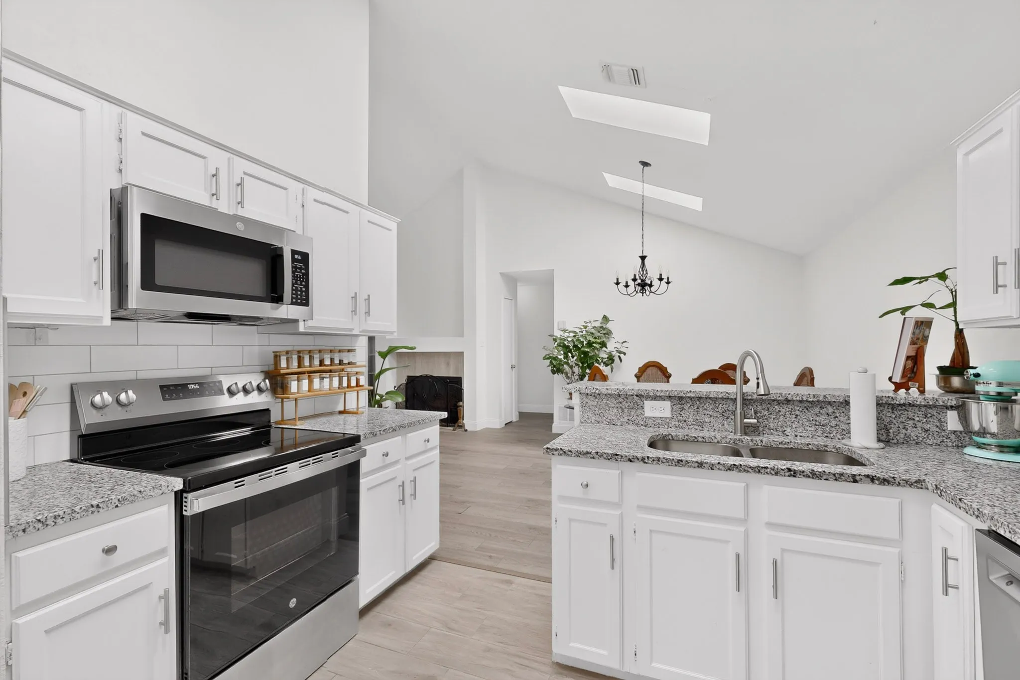 White cabinetry with stainless steel appliances, granite countertops, and a subway tile backsplash