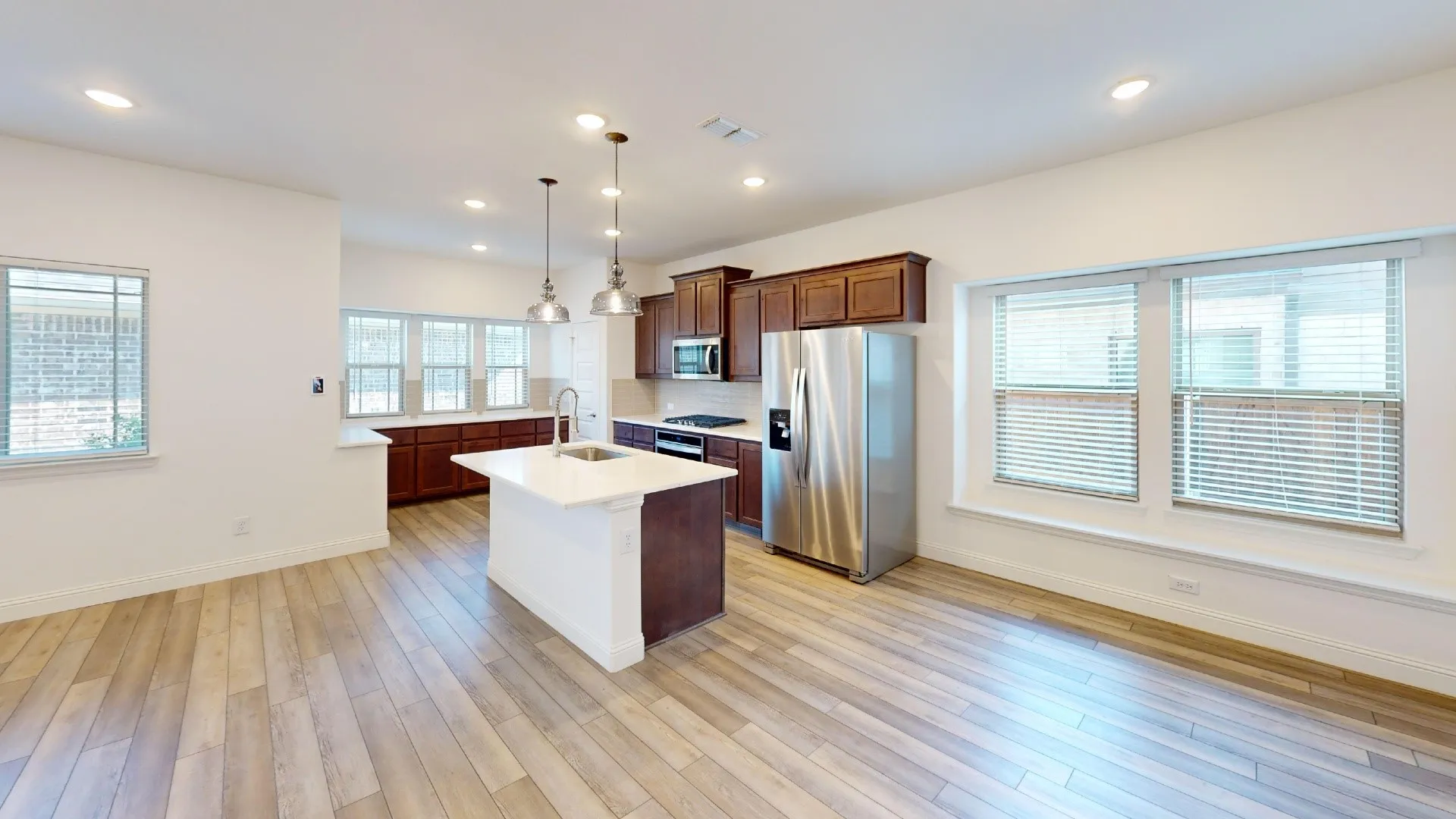 Open-concept kitchen and living area featuring wood-finish flooring, recessed lighting, and ample natural light