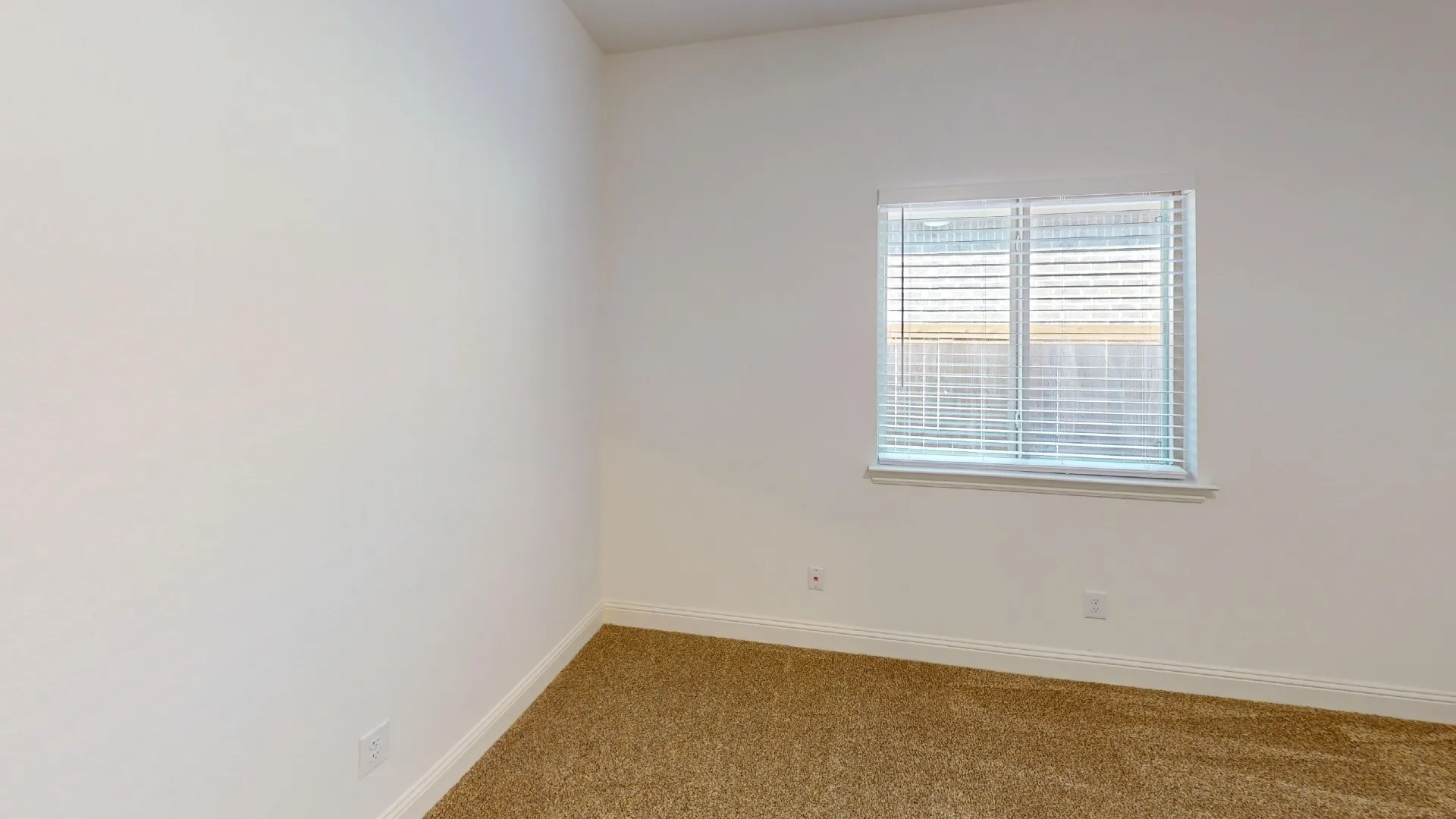 Carpeted flooring, white walls, and a window with blinds
