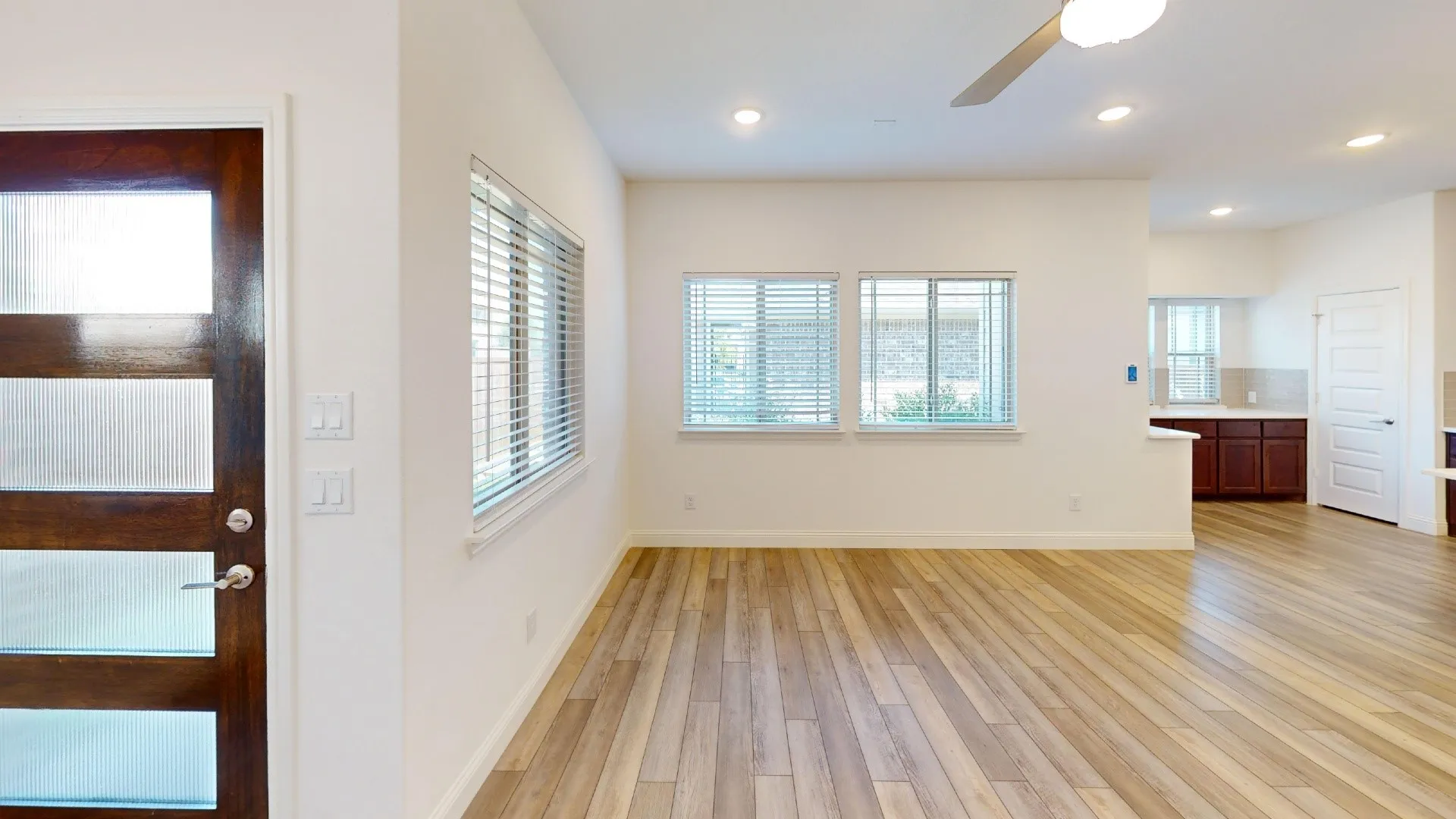 Wood-finish flooring throughout, multiple windows with blinds, recessed lighting, and a contemporary ceiling fan