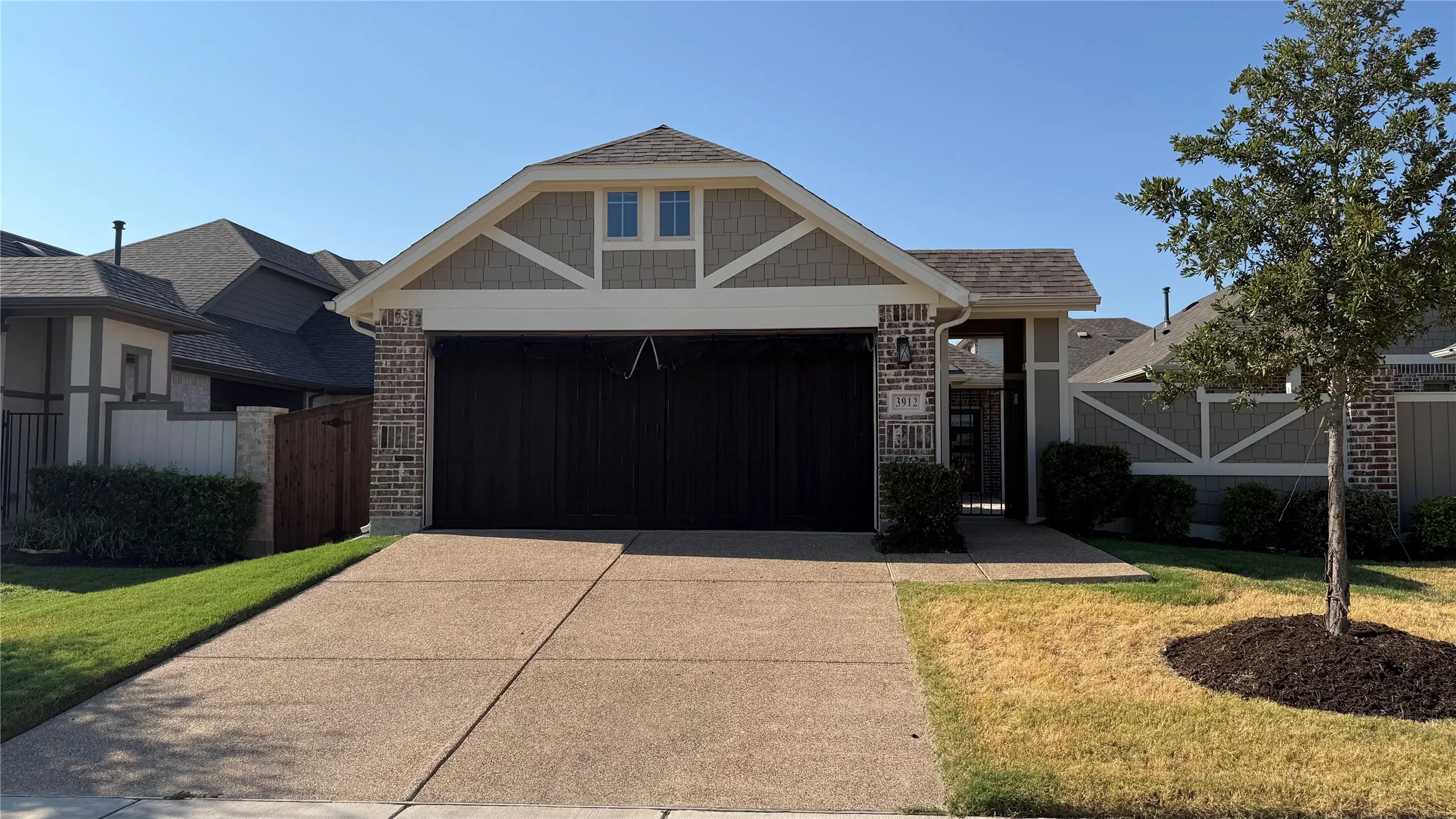 Brick and siding exterior with decorative gable trim, attached garage, and concrete driveway