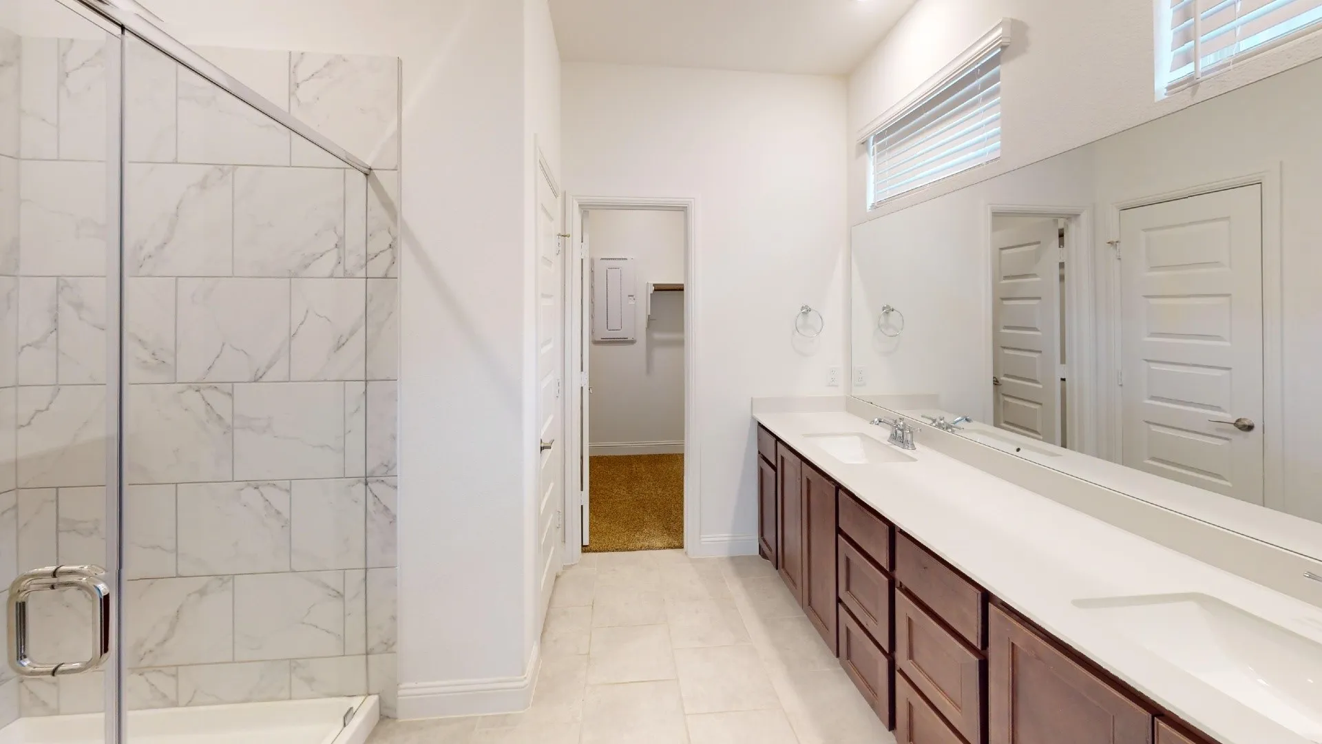 Walk-in shower with clear glass enclosure and marble-look tile surround