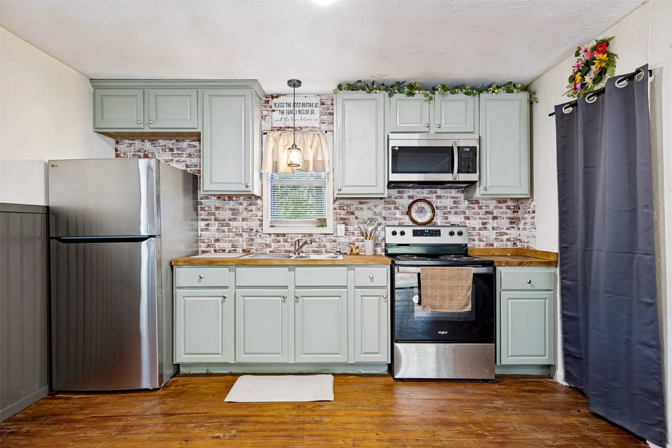 Kitchen featuring light-toned cabinetry, wood-finish countertops, and a brick-style backsplash