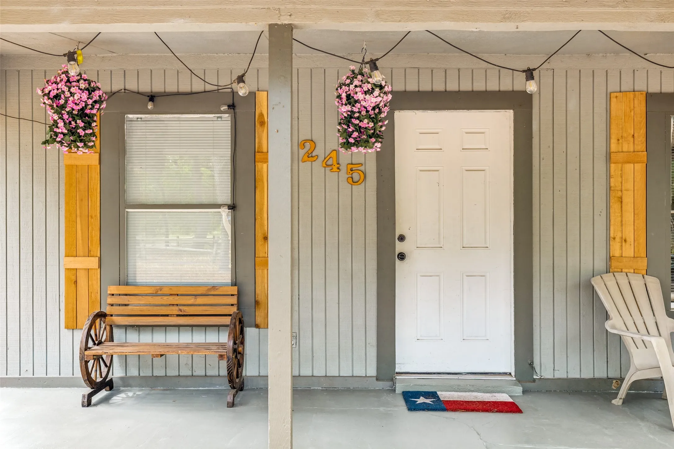 Covered porch entry featuring vertical siding, a paneled door, and two windows with decorative shutters