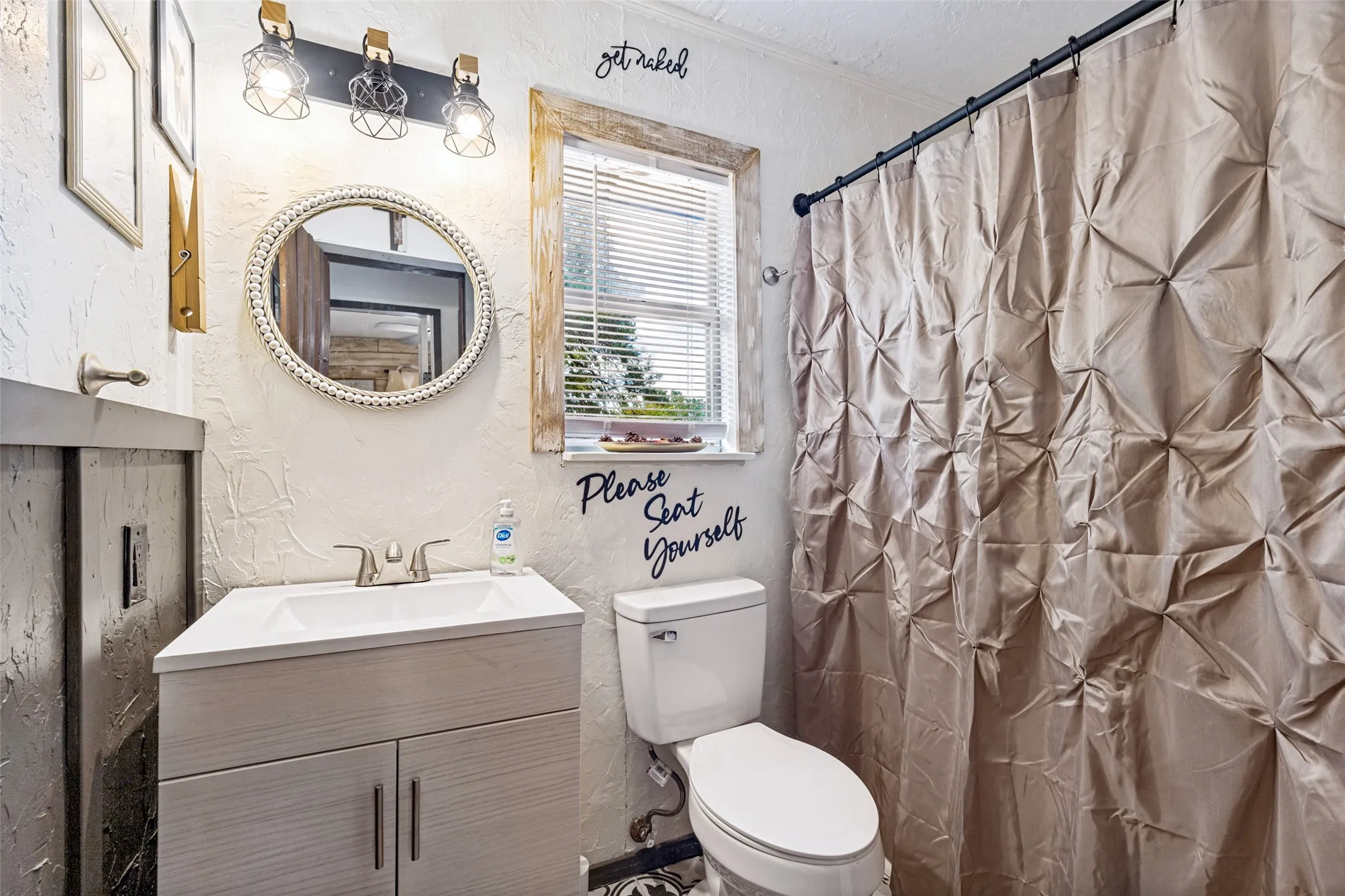 Modern vanity with integrated sink, brushed nickel faucet, and a decorative round mirror