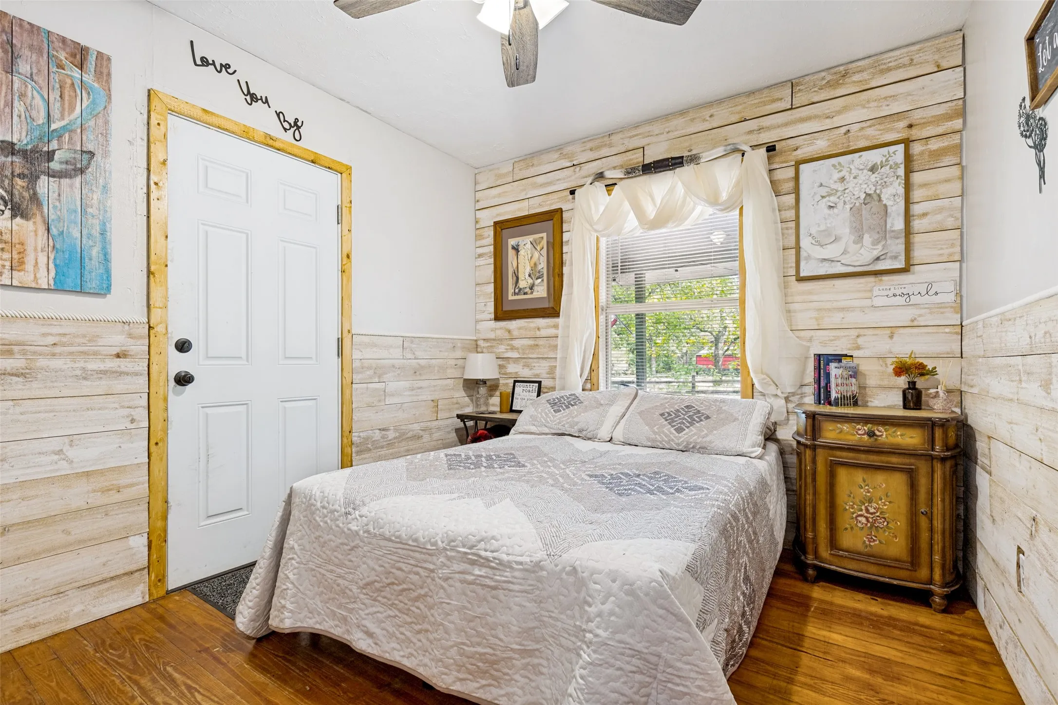 White paneled door with wood-finish trim, wood-finish flooring, and white shiplap-style wall paneling