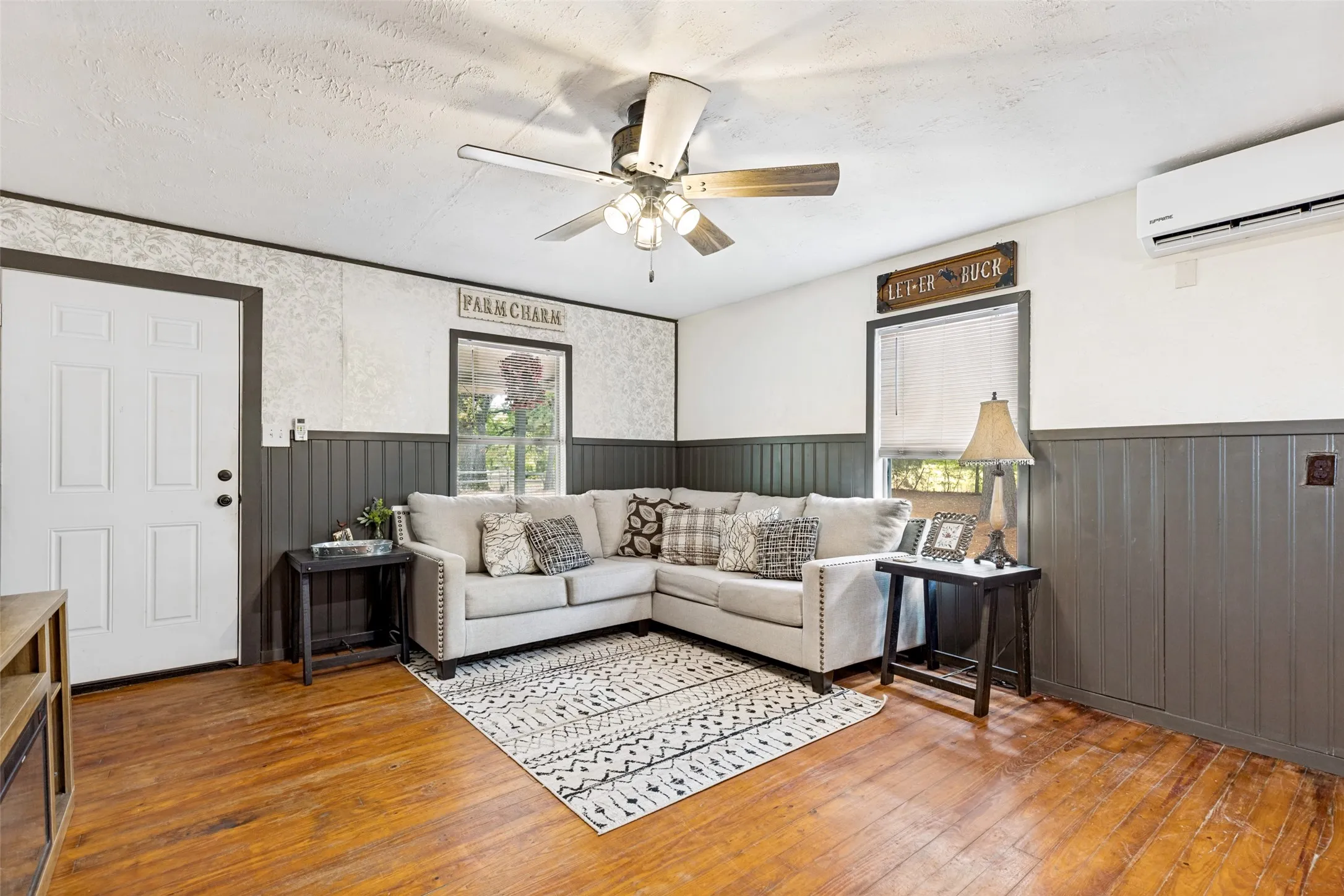 Hardwood flooring, painted paneling, ceiling fan with integrated lighting, window with blinds, and white entry door