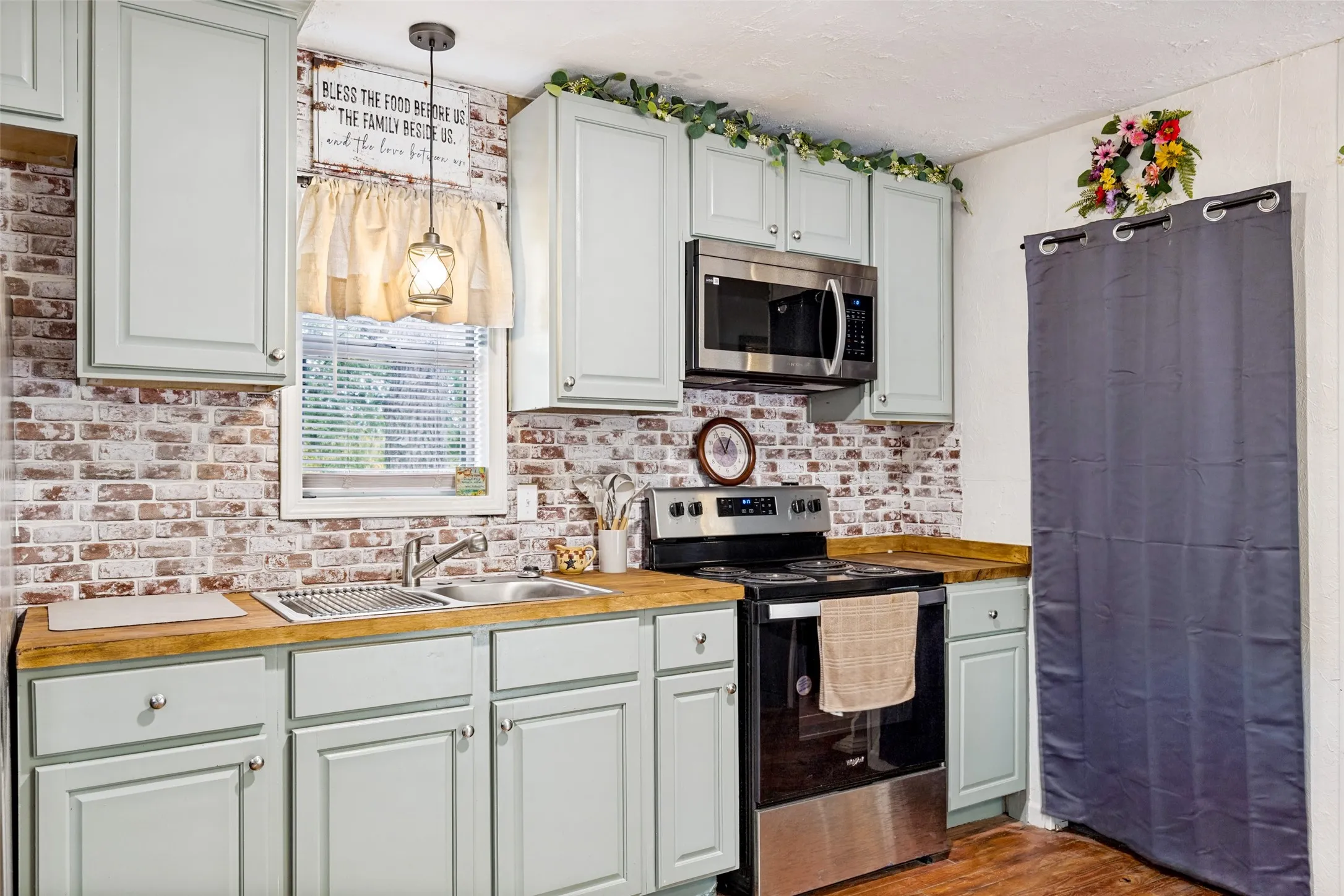 Kitchen featuring light-toned cabinetry, wood-finish countertops, stainless steel appliances, and a brick-patterned backsplash