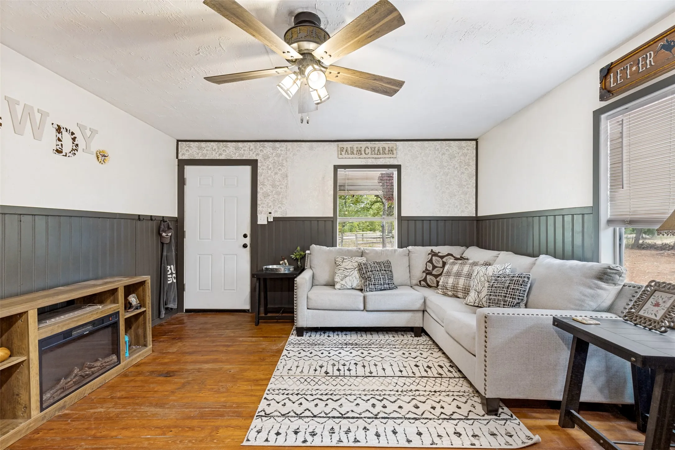 Wood-finish flooring throughout, a ceiling fan with light kit, and a paneled entry door
