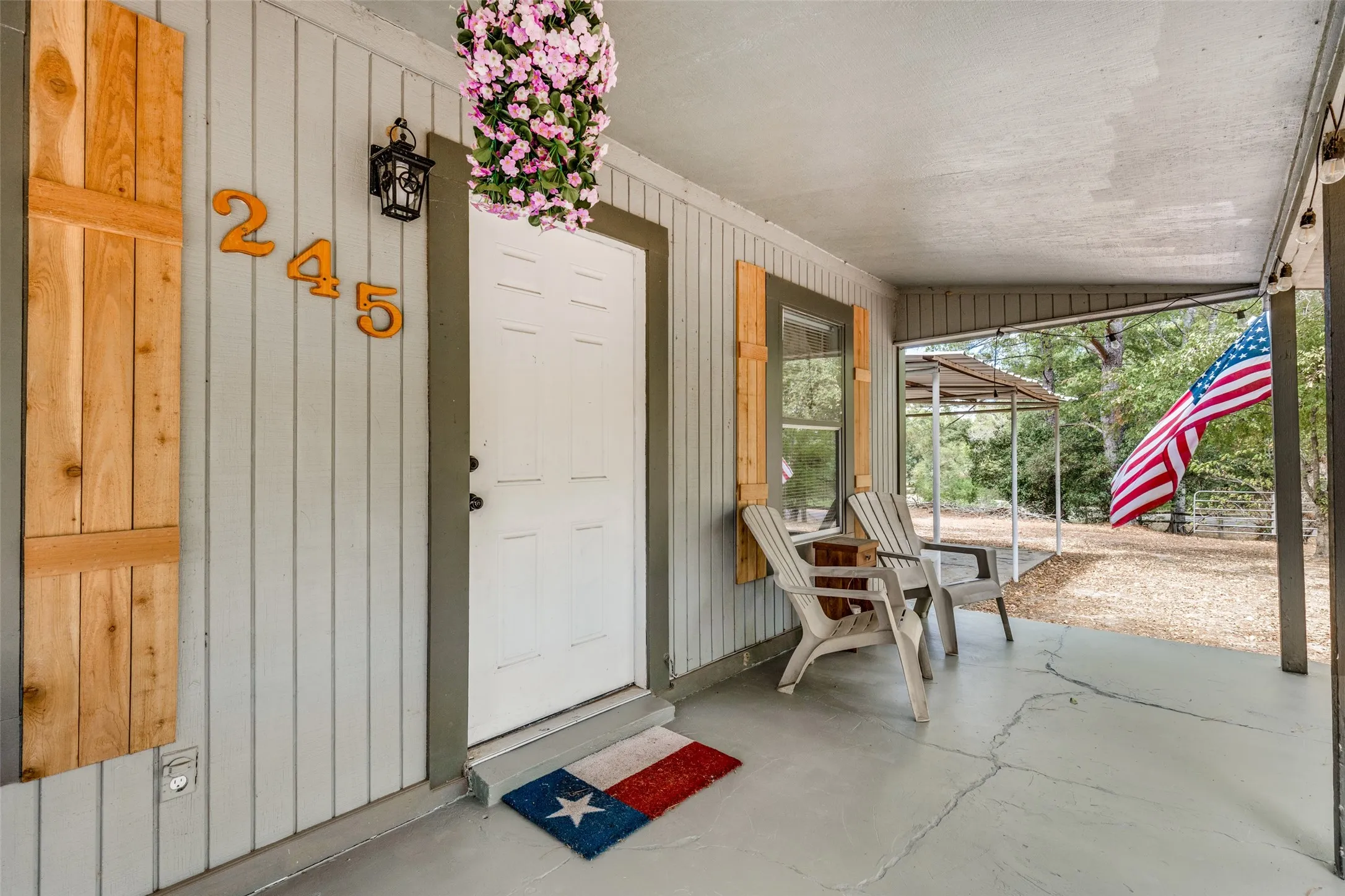 Covered porch entry featuring vertical siding and natural wood shutters