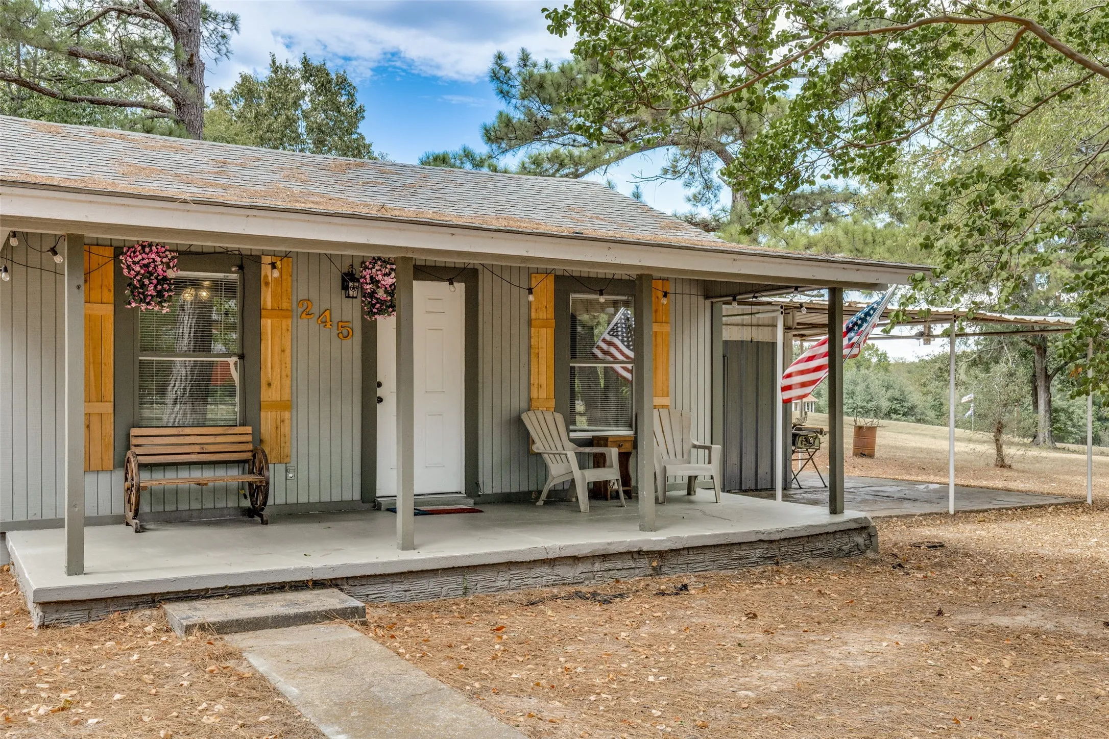 Expansive covered front porch with a concrete surface and vertical siding