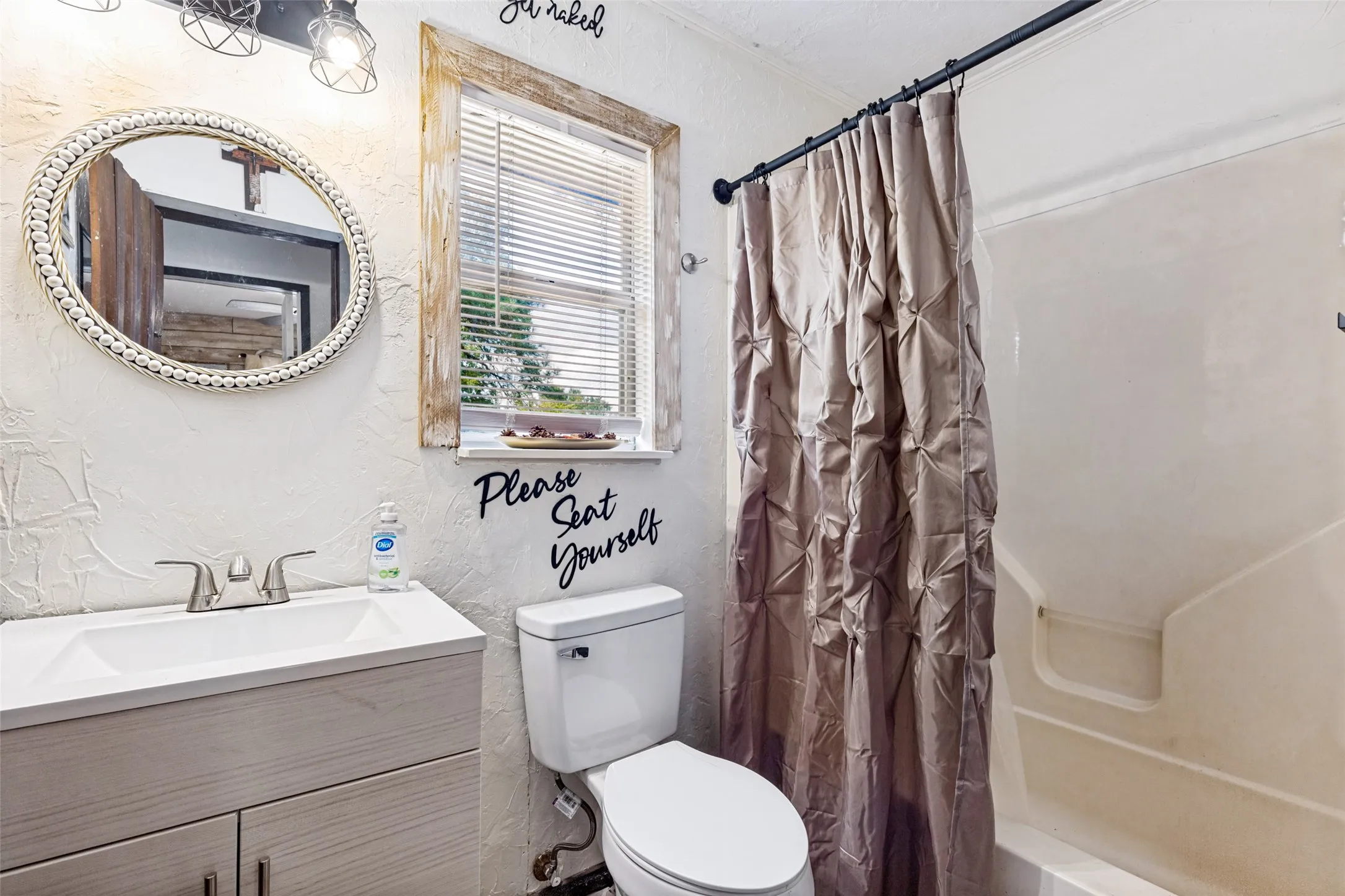 Vanity with integrated sink, brushed nickel faucet, window with blinds, and white toilet