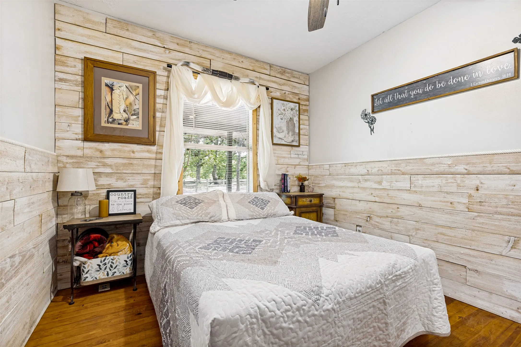 Wood-finish flooring, accent wall with horizontal paneling, vaulted ceiling, and window with natural light