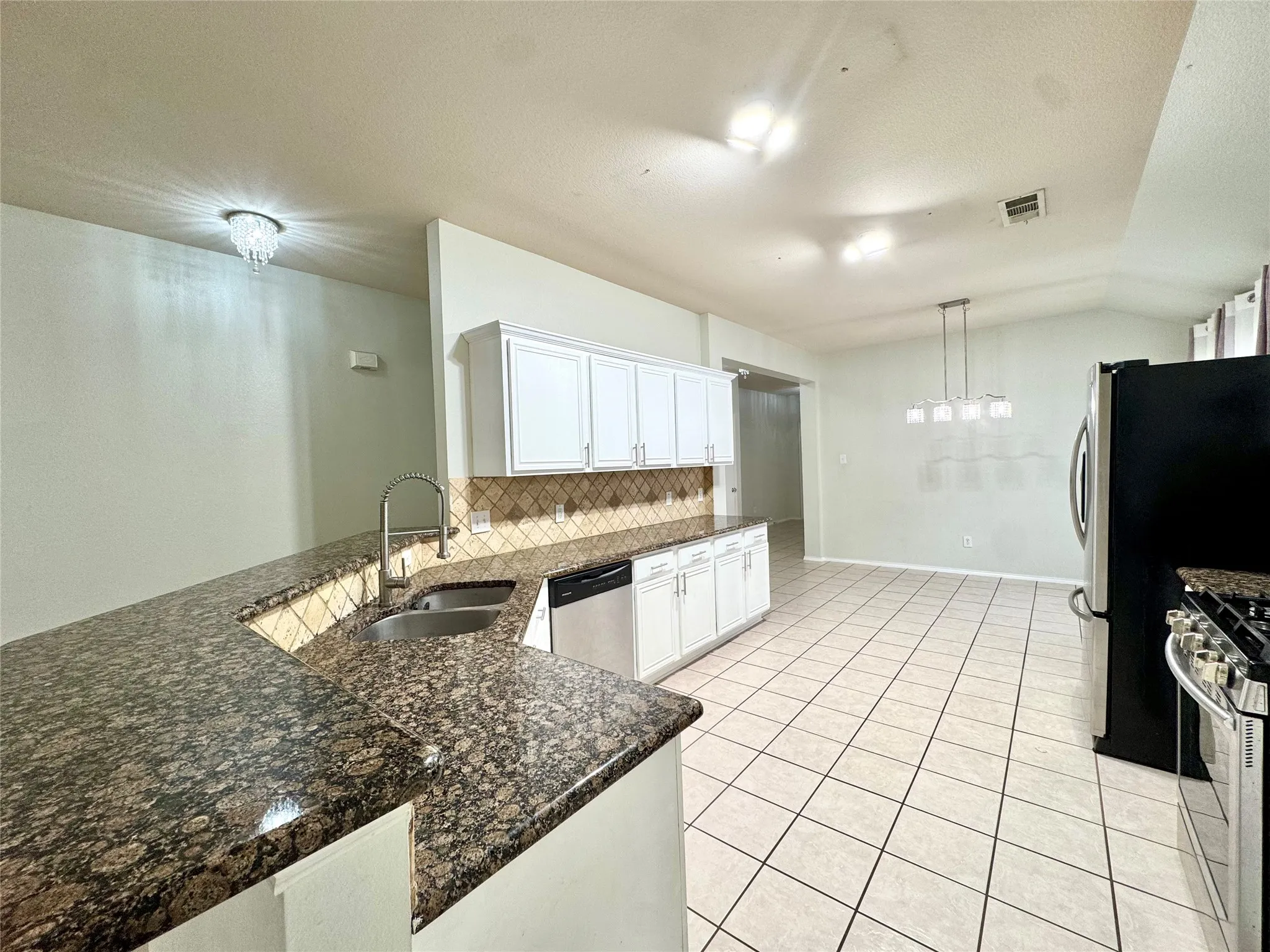 Kitchen featuring granite countertops, white cabinetry, a stainless steel sink with a high-arc faucet, a tiled backsplash, and tile flooring