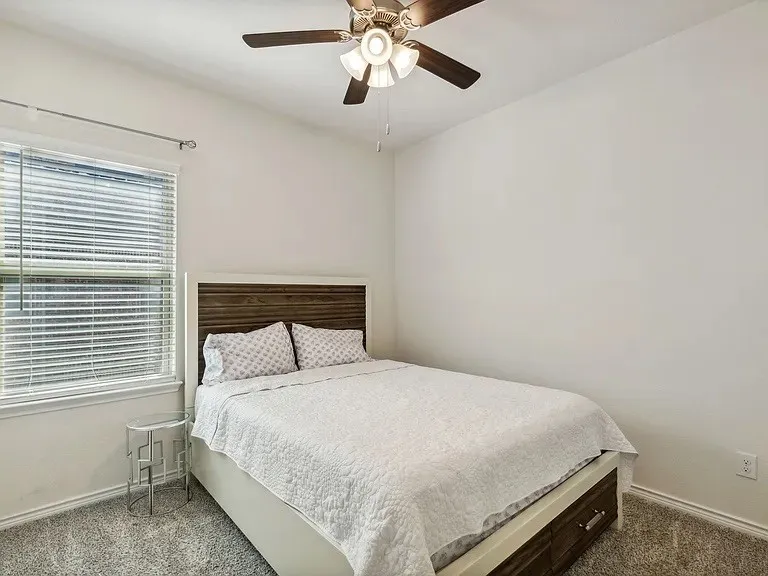 Carpeted bedroom featuring baseboards and ceiling fan