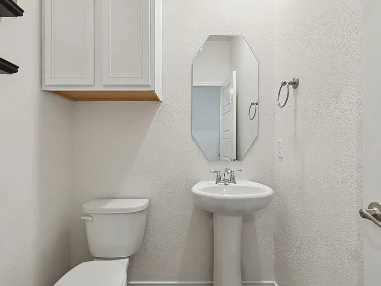 Bathroom with a textured wall, toilet, and a sink