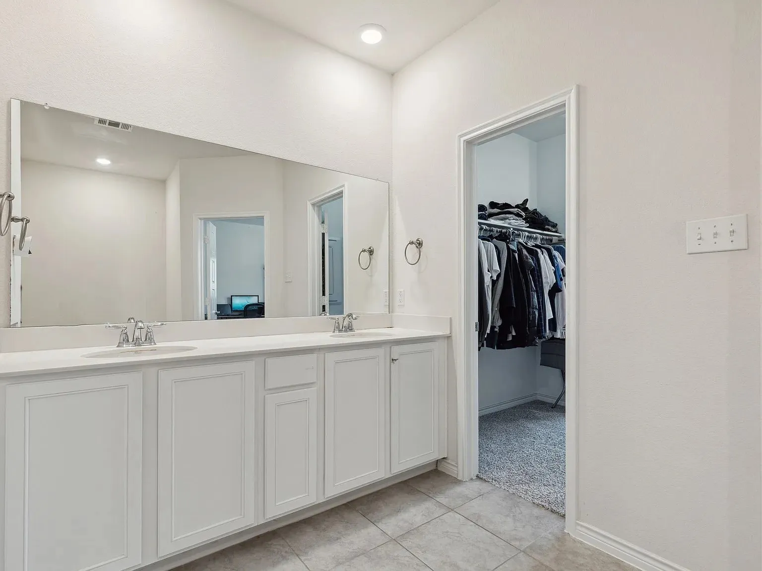 Bathroom with a sink, a spacious closet, tile patterned flooring, visible vents, and double vanity