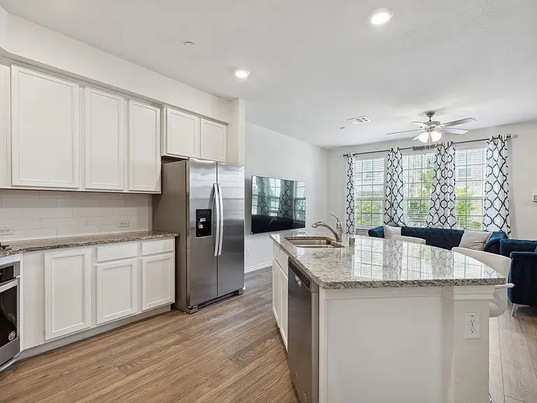 Kitchen featuring stainless steel appliances, a ceiling fan, a sink, light wood-type flooring, and open floor plan