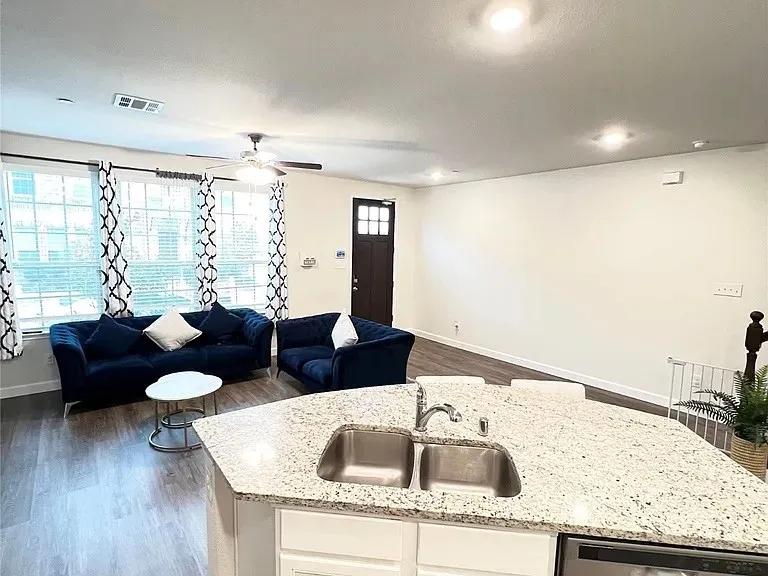 Kitchen with visible vents, dishwasher, a ceiling fan, a sink, and open floor plan