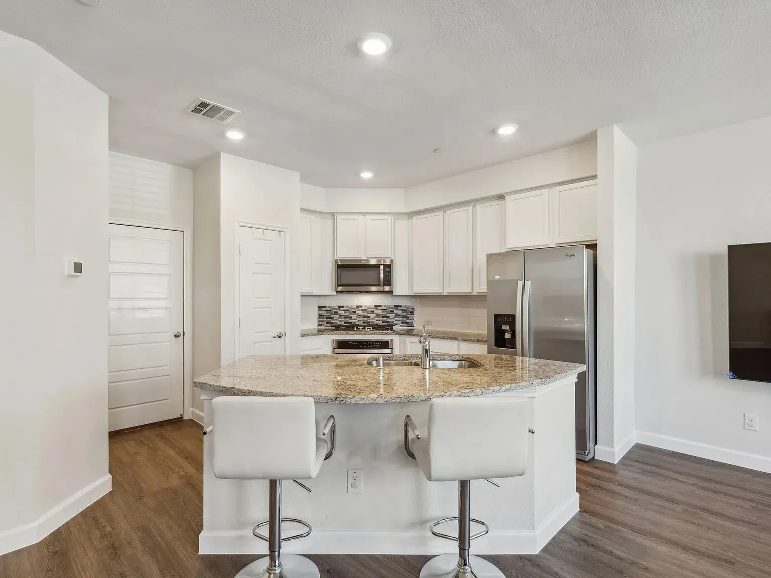 Kitchen featuring a sink, appliances with stainless steel finishes, visible vents, white cabinets, and decorative backsplash