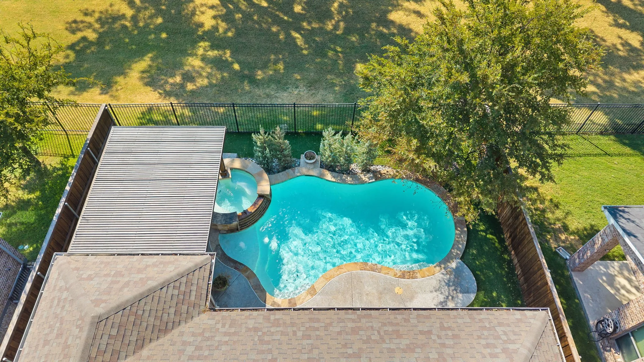 Aerial view of lot featuring pool and green space.