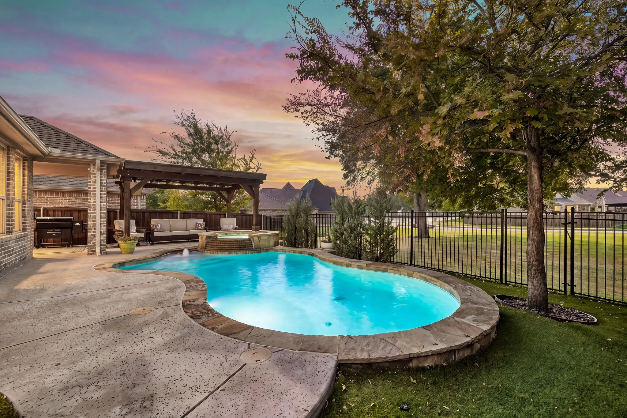 Home features sparkling pool with hot tub and a green space view.