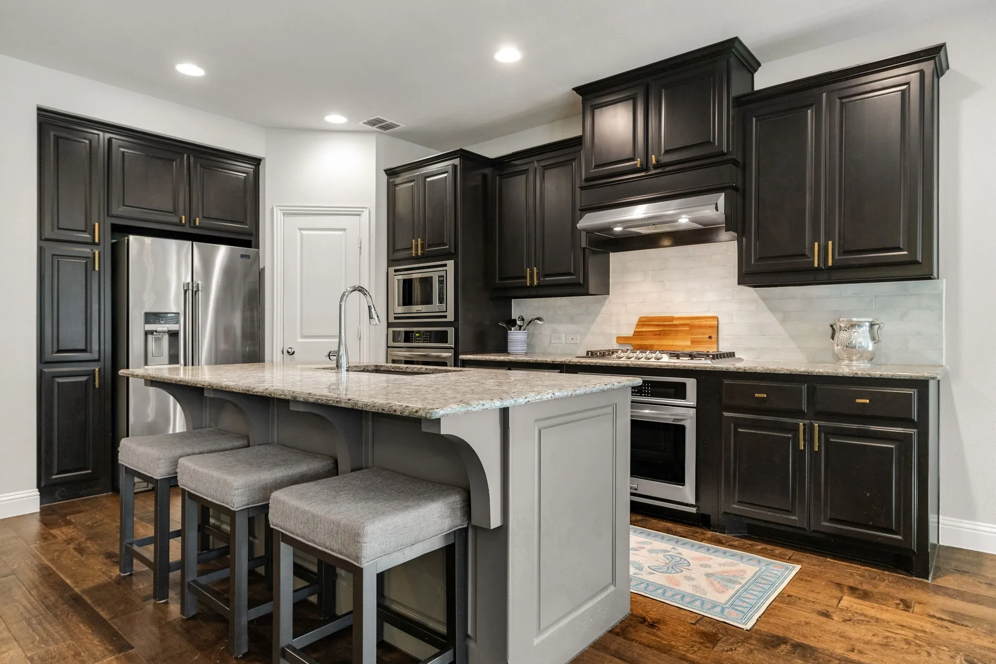Kitchen features rich wood cabinetry and granite counters.