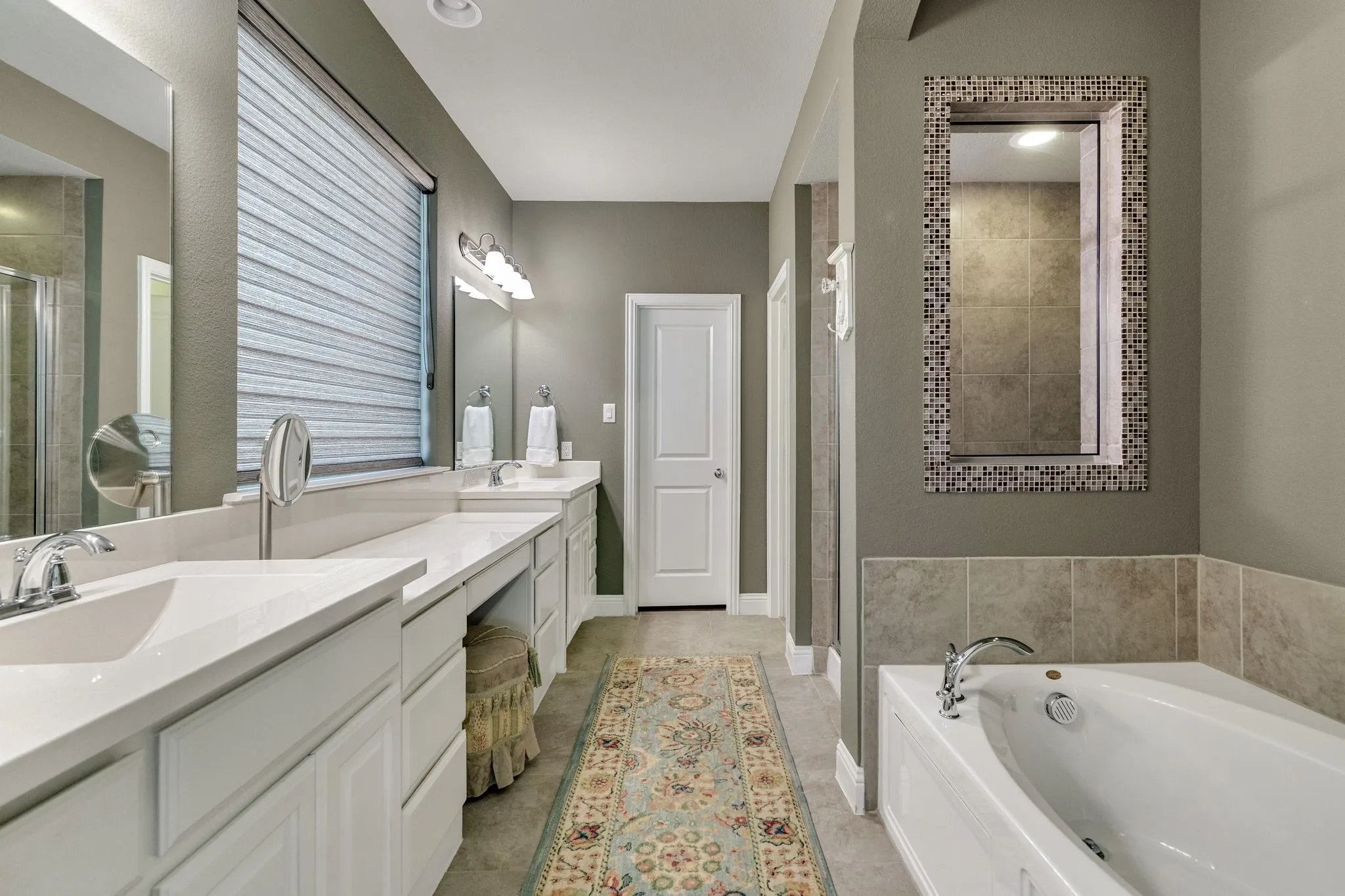 En-suite bath with dual sinks and dedicated vanity.