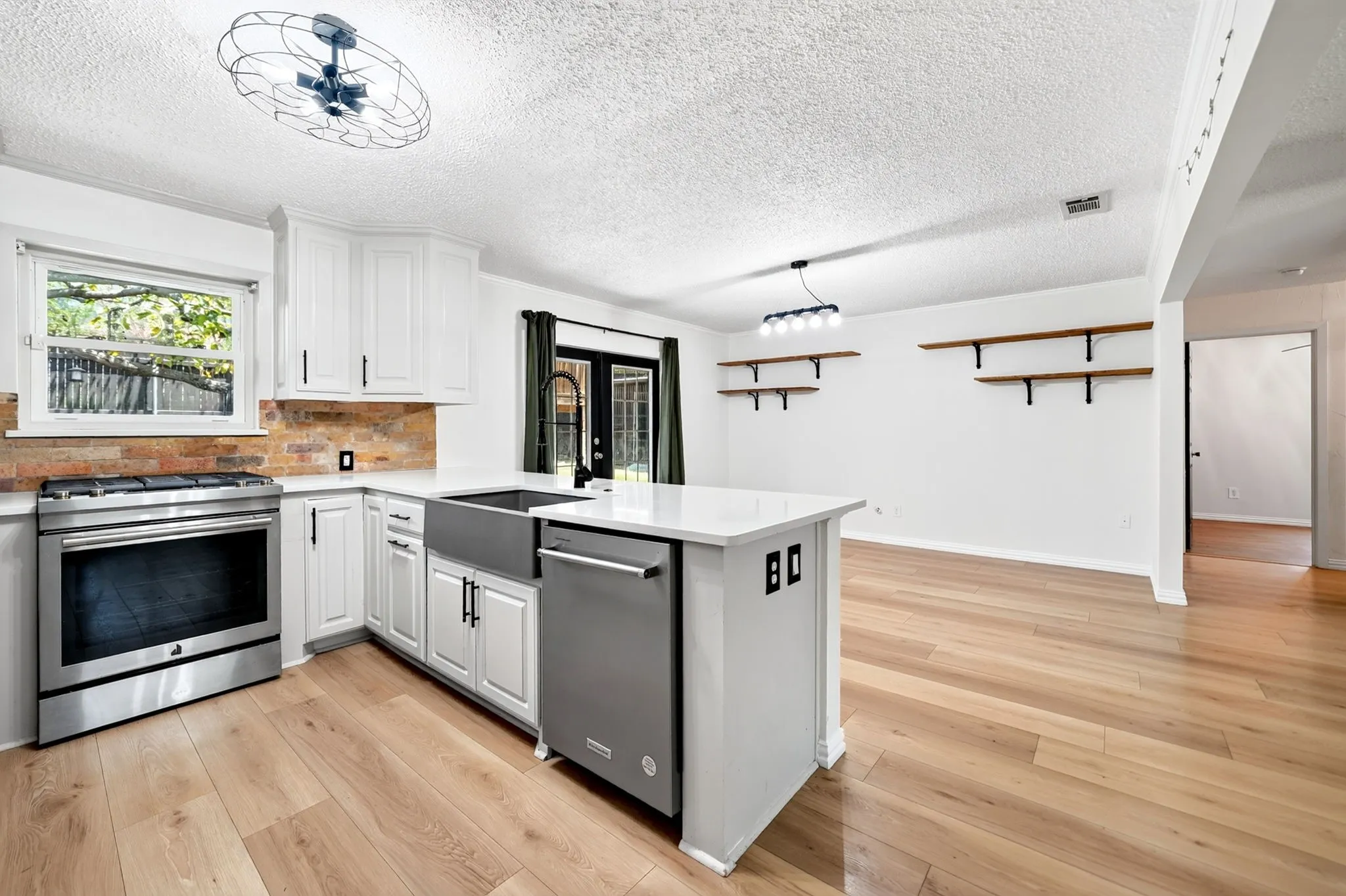 Kitchen featuring stainless steel appliances, white cabinetry, a farmhouse sink, and light wood-finish flooring